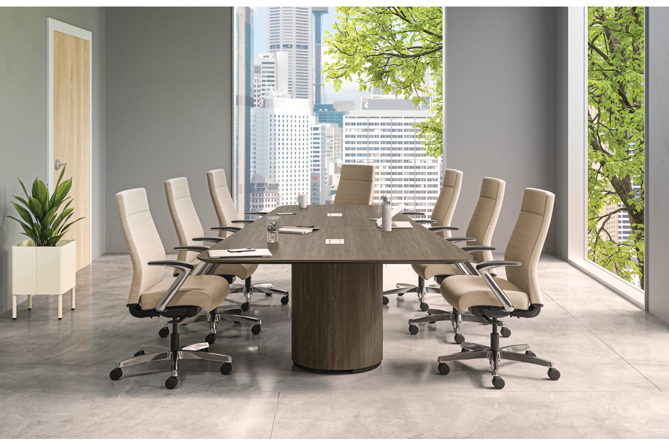A modern and minimalist conference room with a large wooden table surrounded by white office chairs, overlooking a cityscape through the large windows.