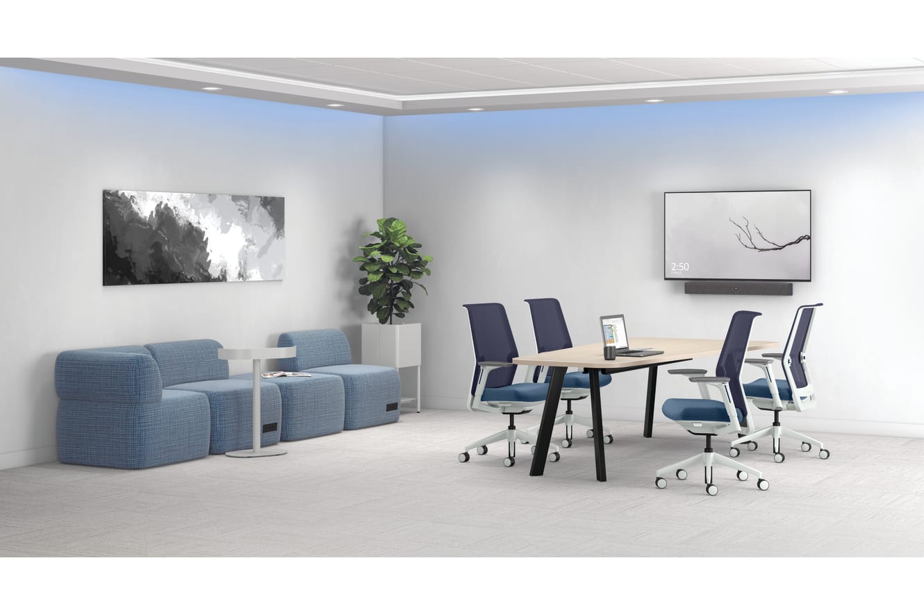 A modern and minimalist office space with gray and blue furniture, including chairs and a table, along with artwork and a potted plant decorating the walls.