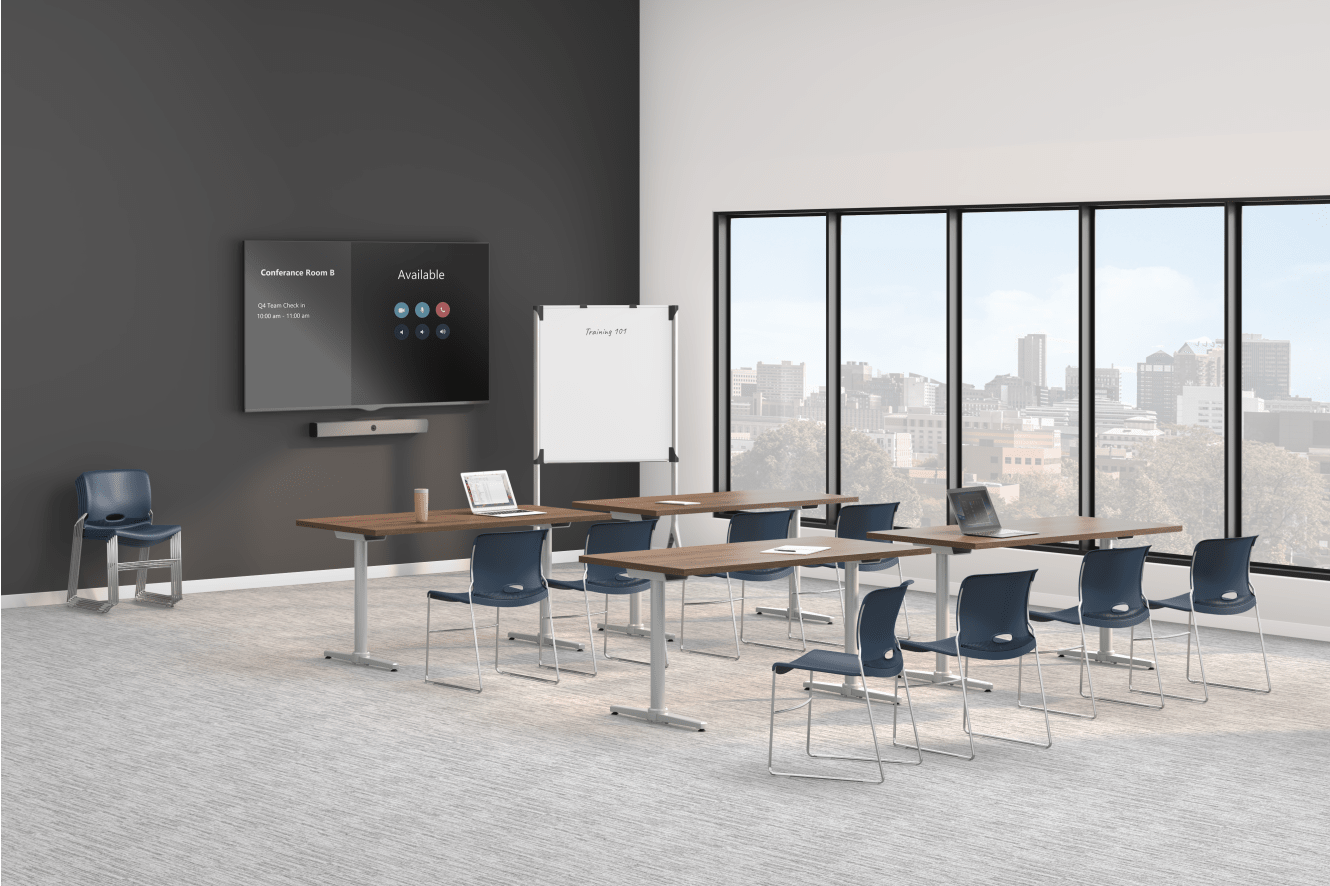 A modern training room with long tables, blue chairs, a wall-mounted display screen, a whiteboard, and large windows overlooking a city skyline.