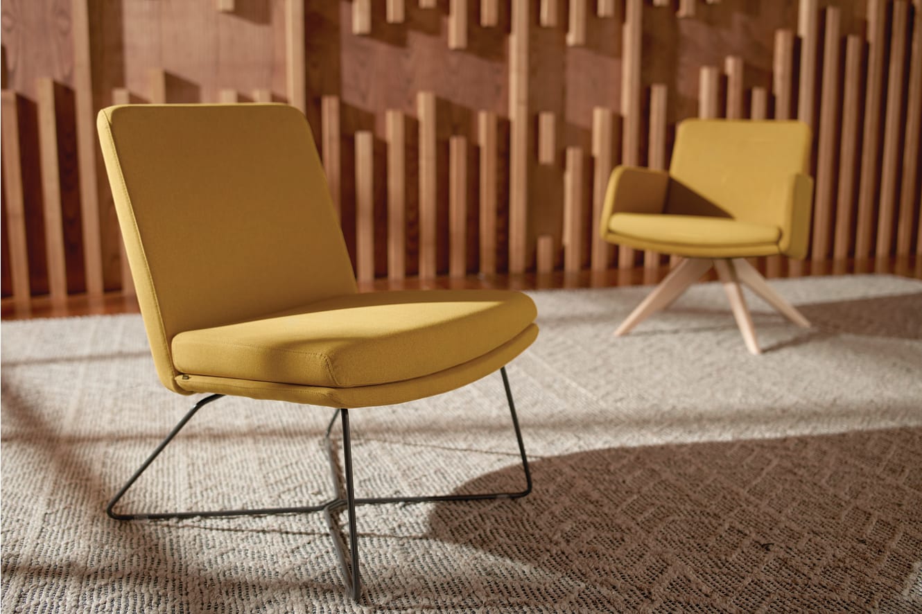 The image shows two yellow chairs with metal frames against a wooden wall background.