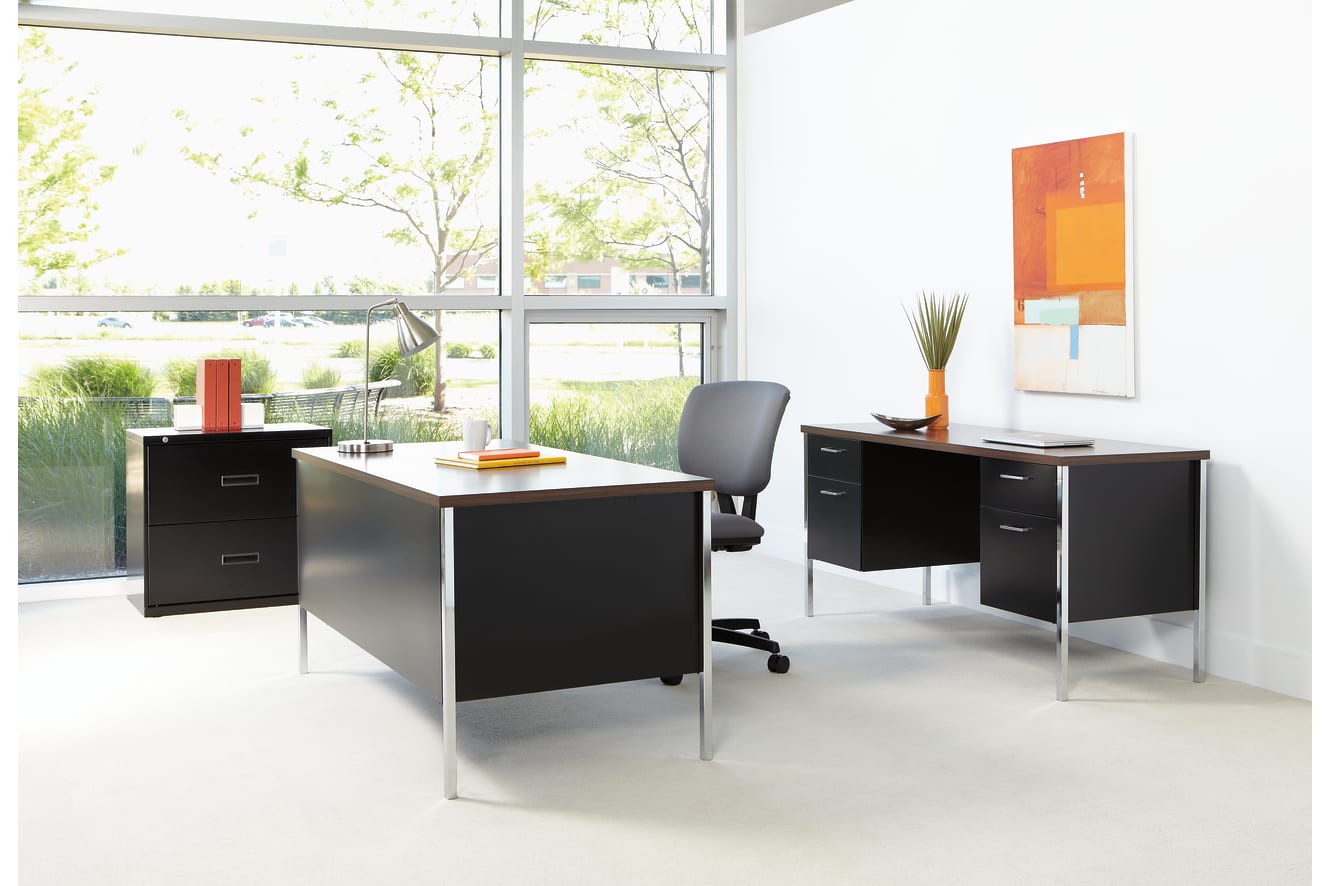 A modern and minimalist office space with sleek black furniture, large windows overlooking greenery, and vibrant artwork on the walls.