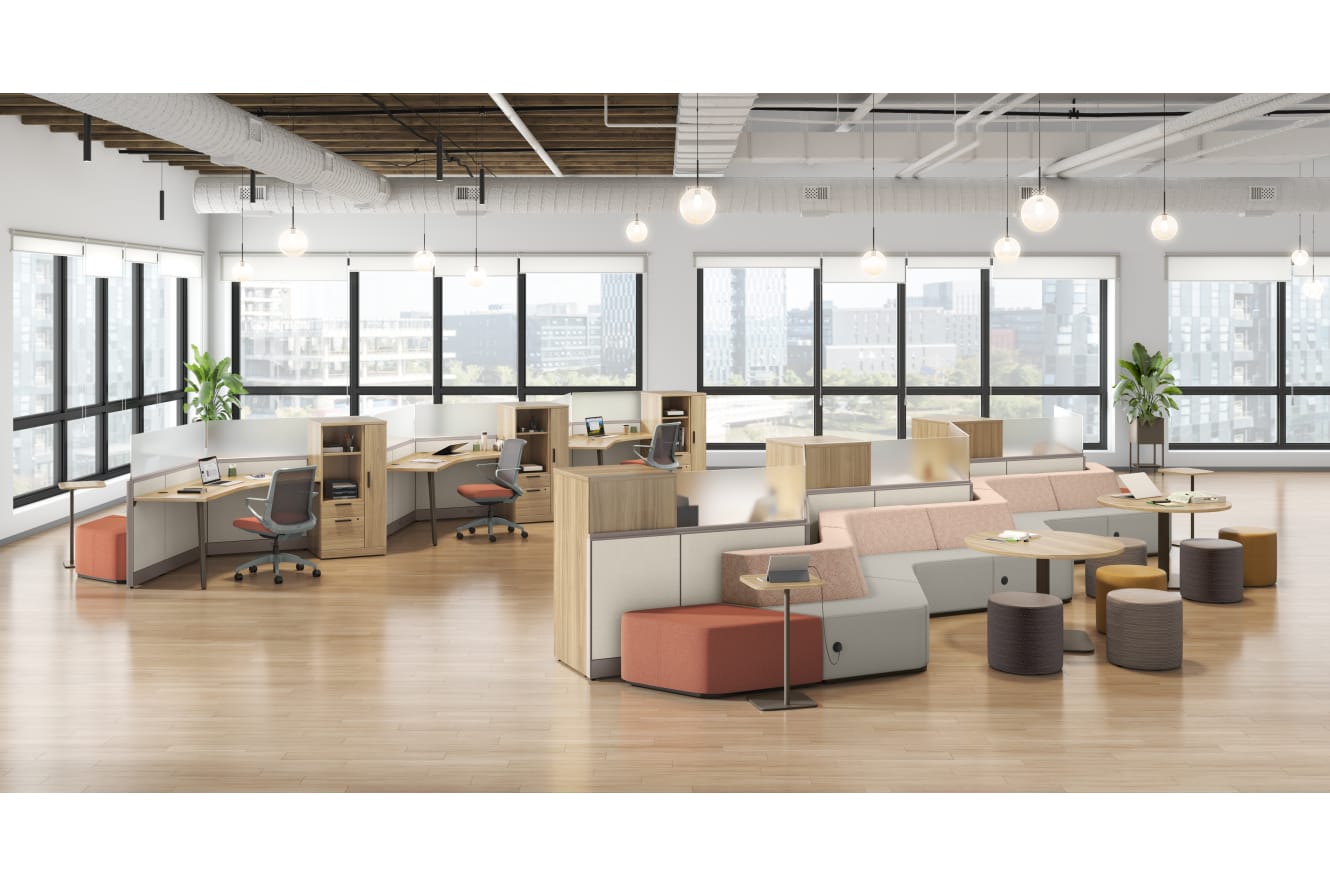 A modern, open-concept office space with cubicles, seating areas, and large windows providing ample natural light.