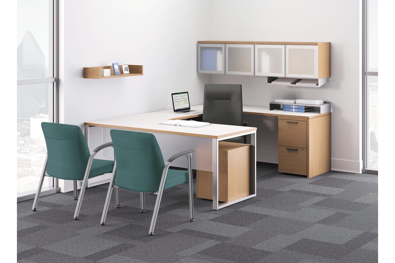 A modern and minimalist office space with a wooden desk, green chairs, and various storage units and shelves on the walls.
