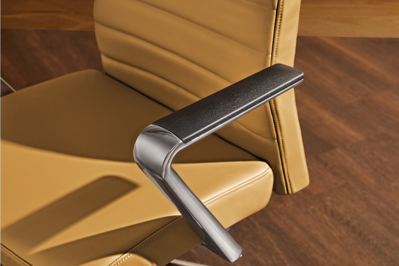 The image shows a close-up view of a chair's armrest, featuring a sleek and modern design with a black padded surface and a metallic frame.