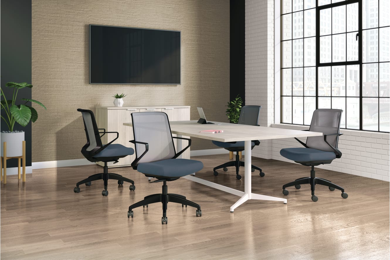 A modern, minimalist office space with a large conference table, comfortable office chairs, and a large wall-mounted display screen, set against a backdrop of large windows and a neutral-toned interior.