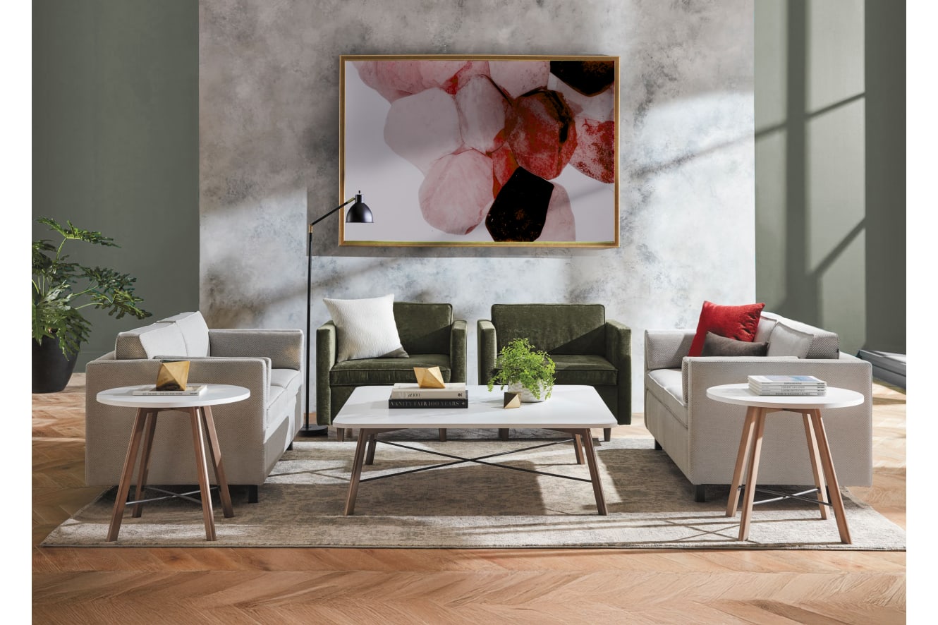 A modern and minimalist living room with plush green sofas, a white coffee table, and a large abstract artwork on the wall, set against a marble-like background.