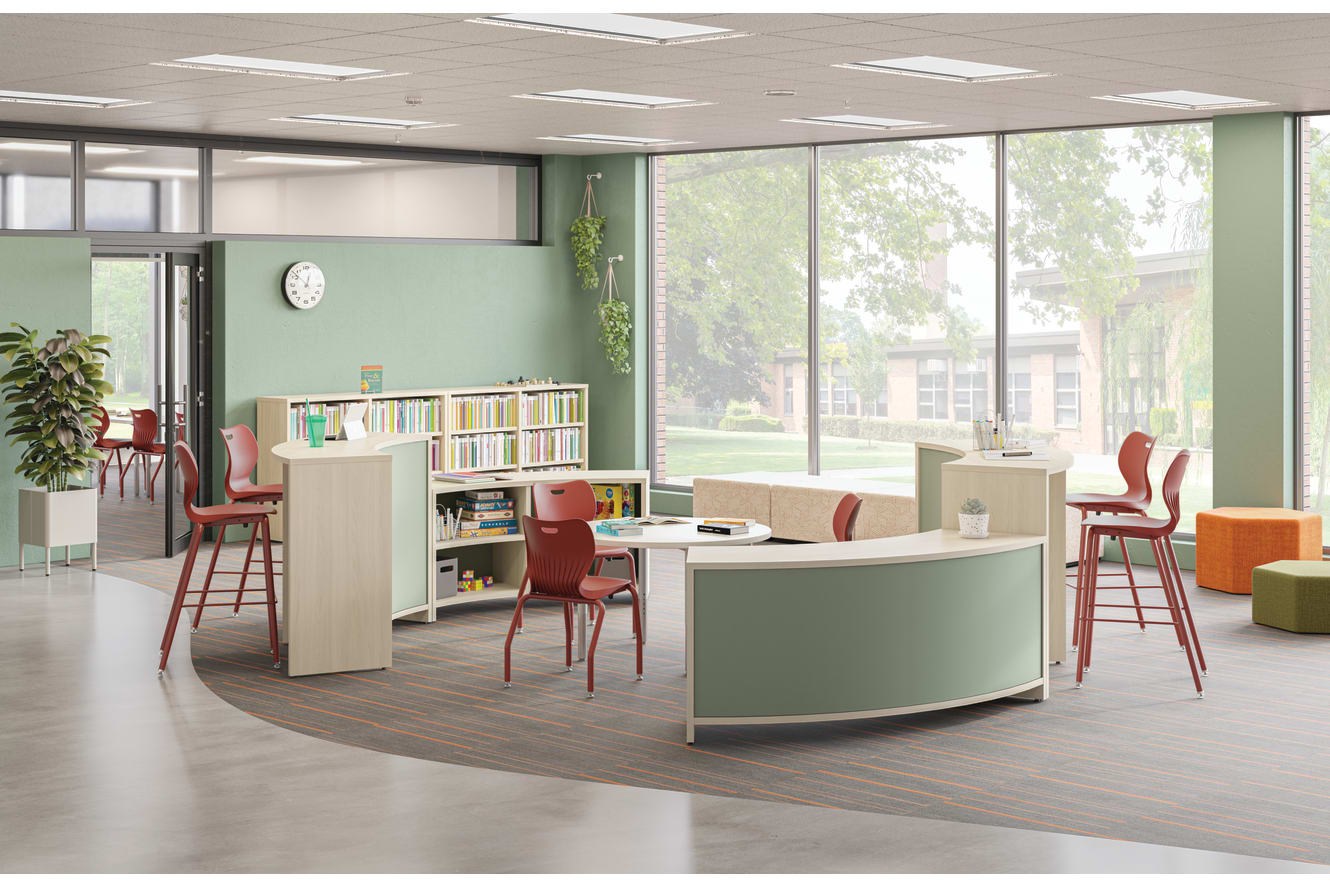 A modern, open-concept office space with a mix of functional and decorative elements, including a curved desk, bookshelves, and colorful chairs, set against a backdrop of large windows overlooking a lush outdoor environment.