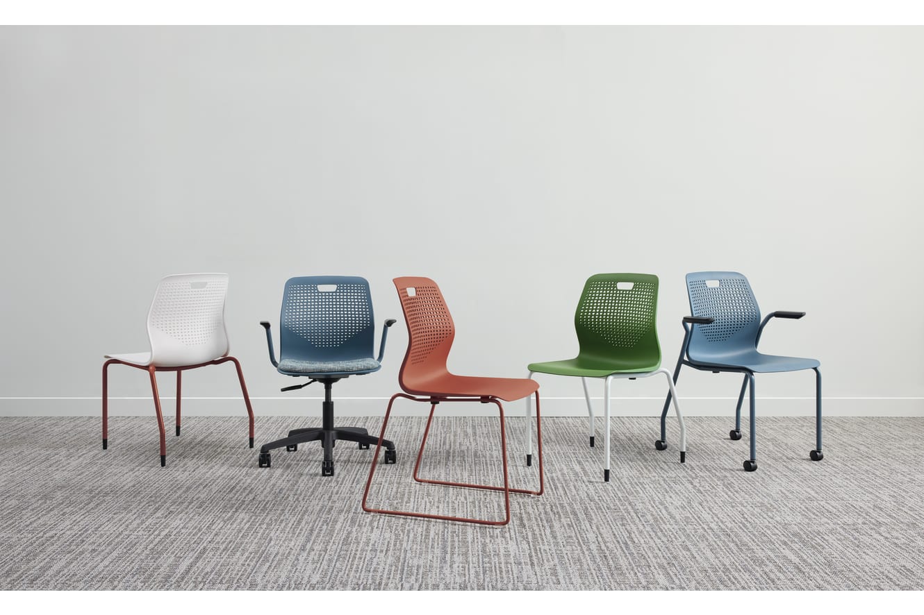 A collection of colorful, modern-looking chairs arranged on a gray tiled floor against a plain white wall.