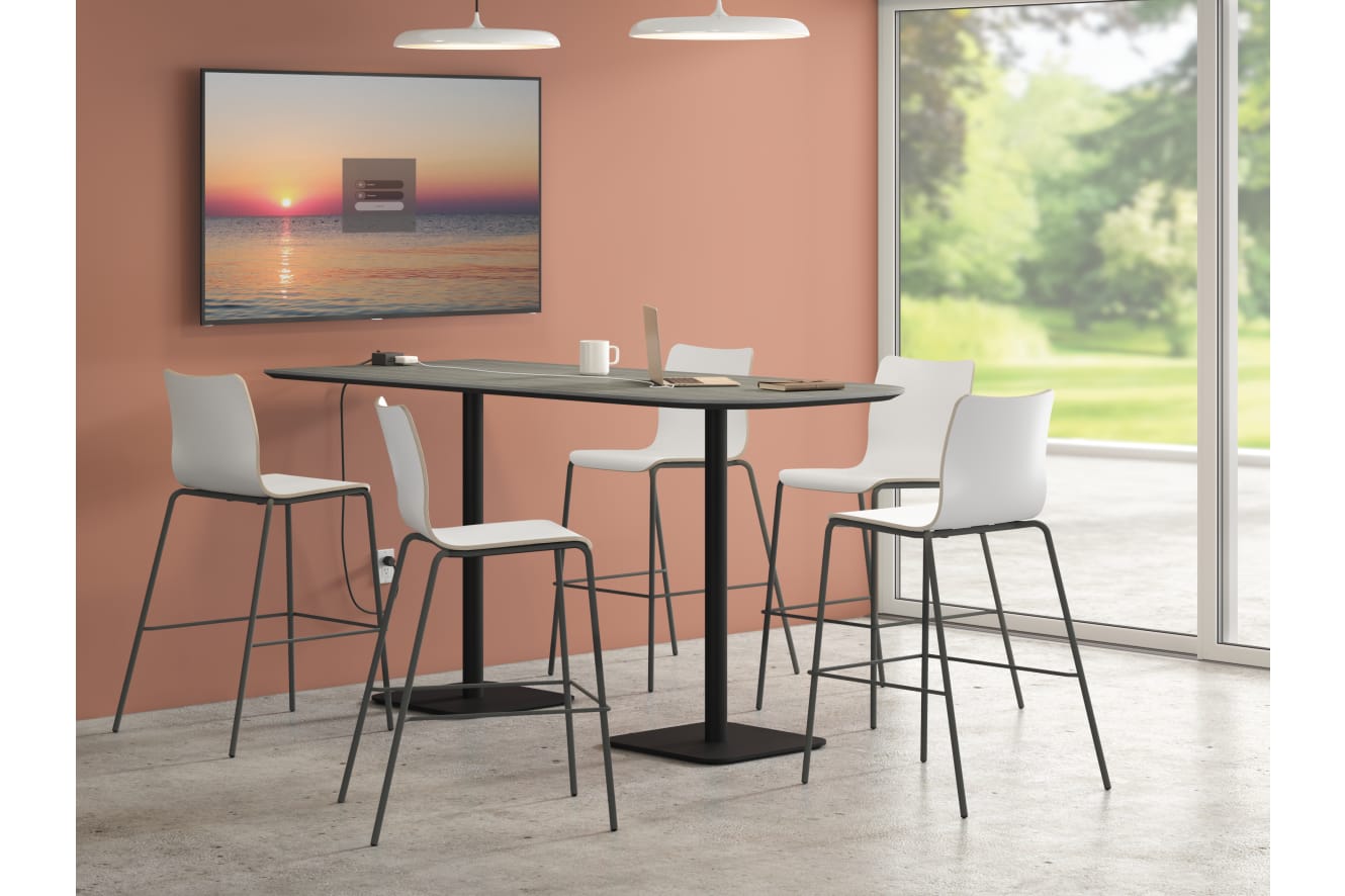 A modern dining area with a sleek black table and white bar stools, set against a backdrop of a serene sunset landscape visible through a large window.