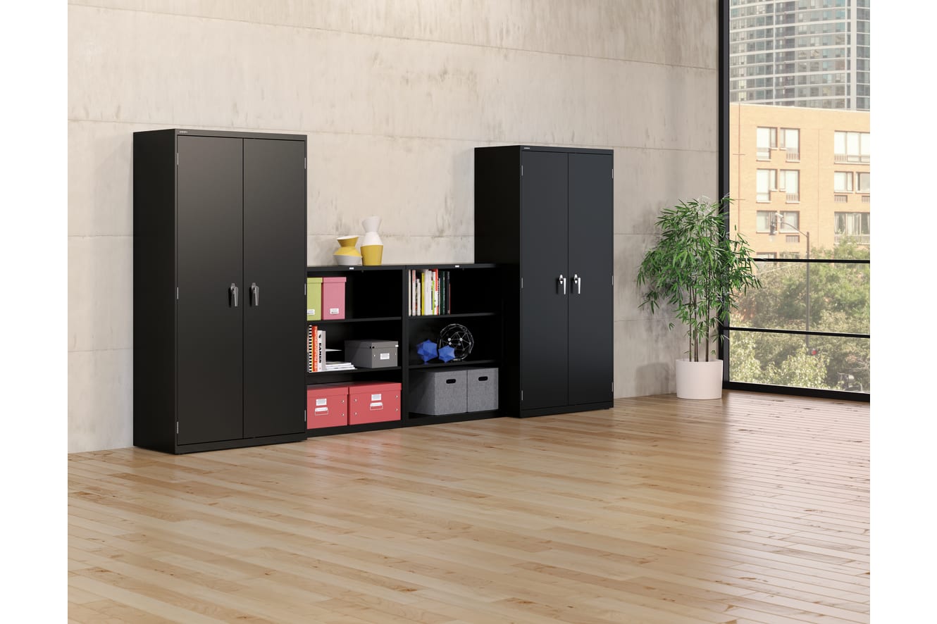 The image depicts a modern and minimalist home office or study space, featuring two black storage cabinets with shelves and compartments, a potted plant, and a large window overlooking a cityscape in the background.