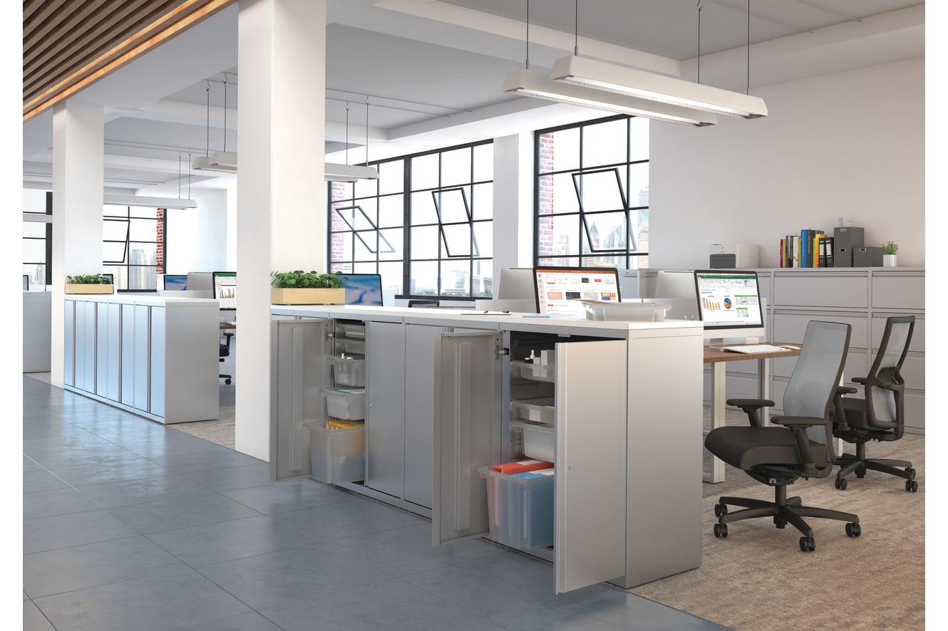 A modern and open-concept office space with a kitchen area, desks, and large windows providing ample natural light.