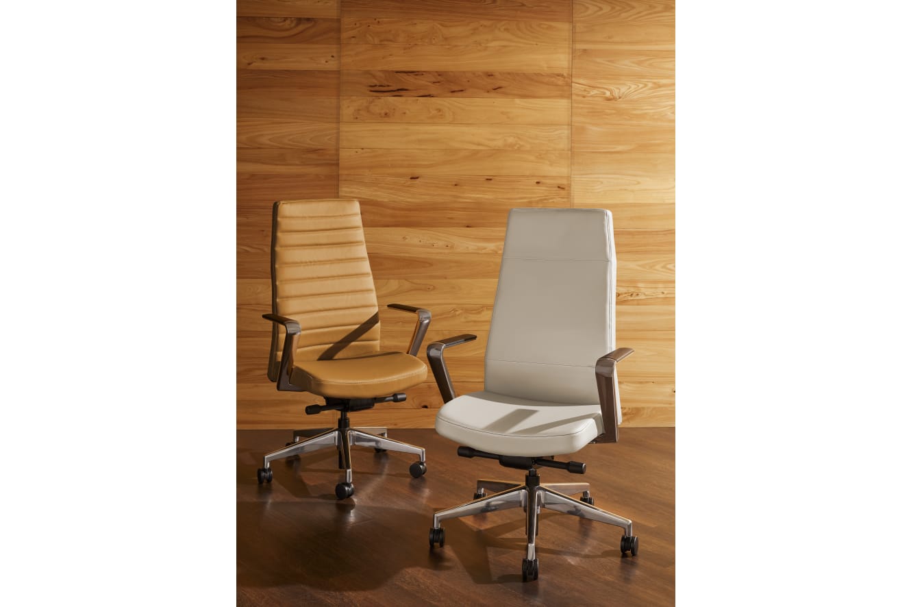 Two modern office chairs with ergonomic designs sit in front of a wooden wall, creating a minimalist and professional workspace environment.