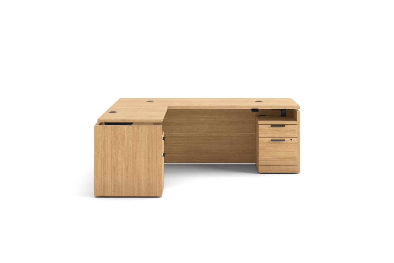 L-shaped executive workstation with woodgrain finish, integrated power access, and pedestal file storage.