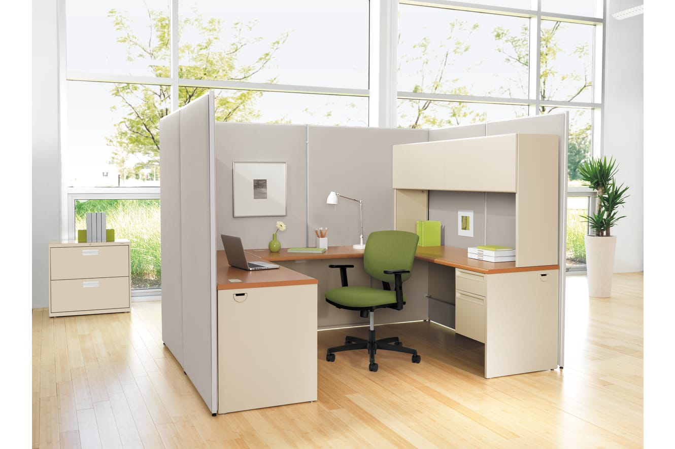 A modern, minimalist office space with cubicles, desks, and chairs arranged in a clean, organized manner, surrounded by large windows that allow natural light to flood the room.