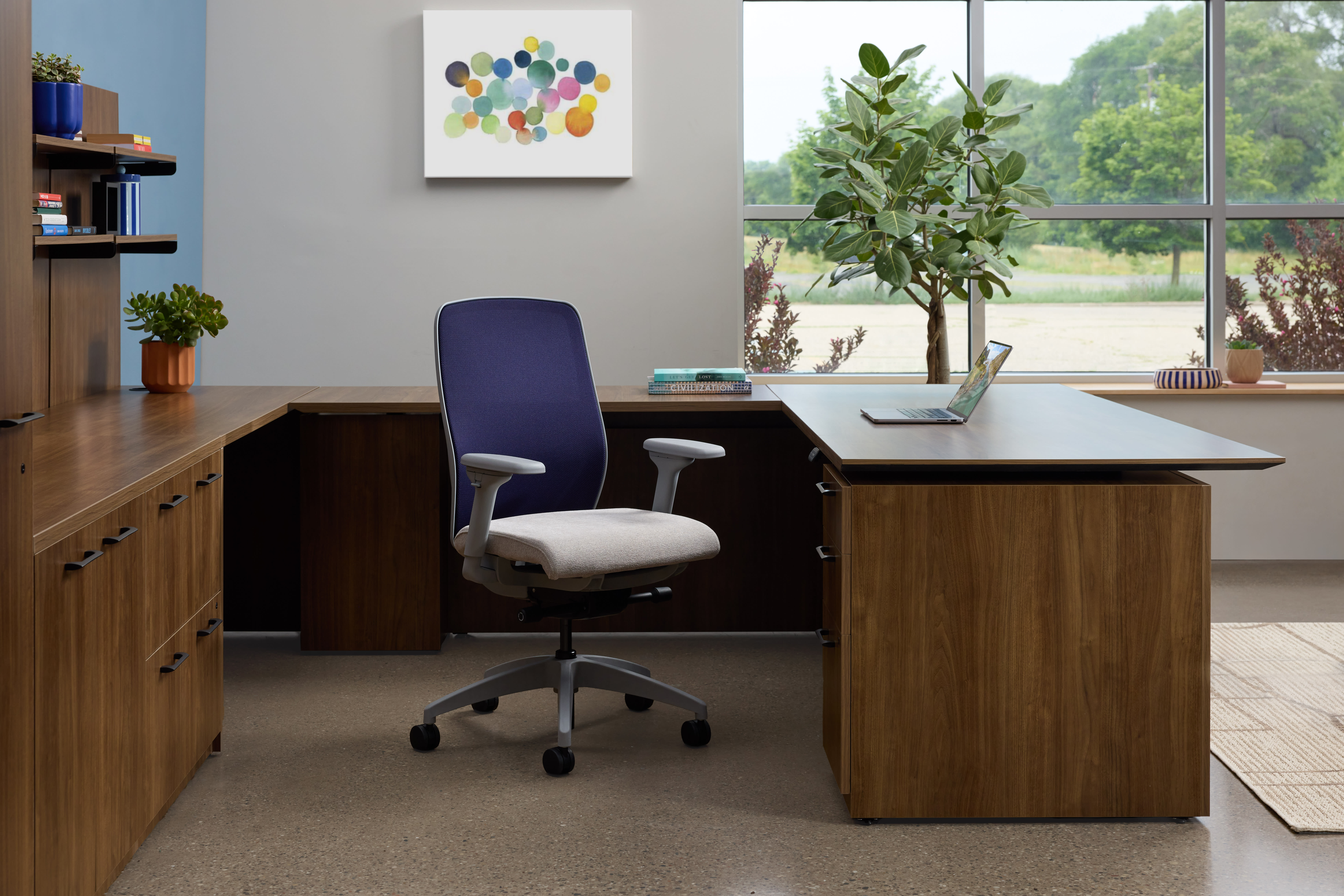 A modern and well-organized home office space with a wooden desk, a comfortable office chair, and a large window overlooking a natural landscape.