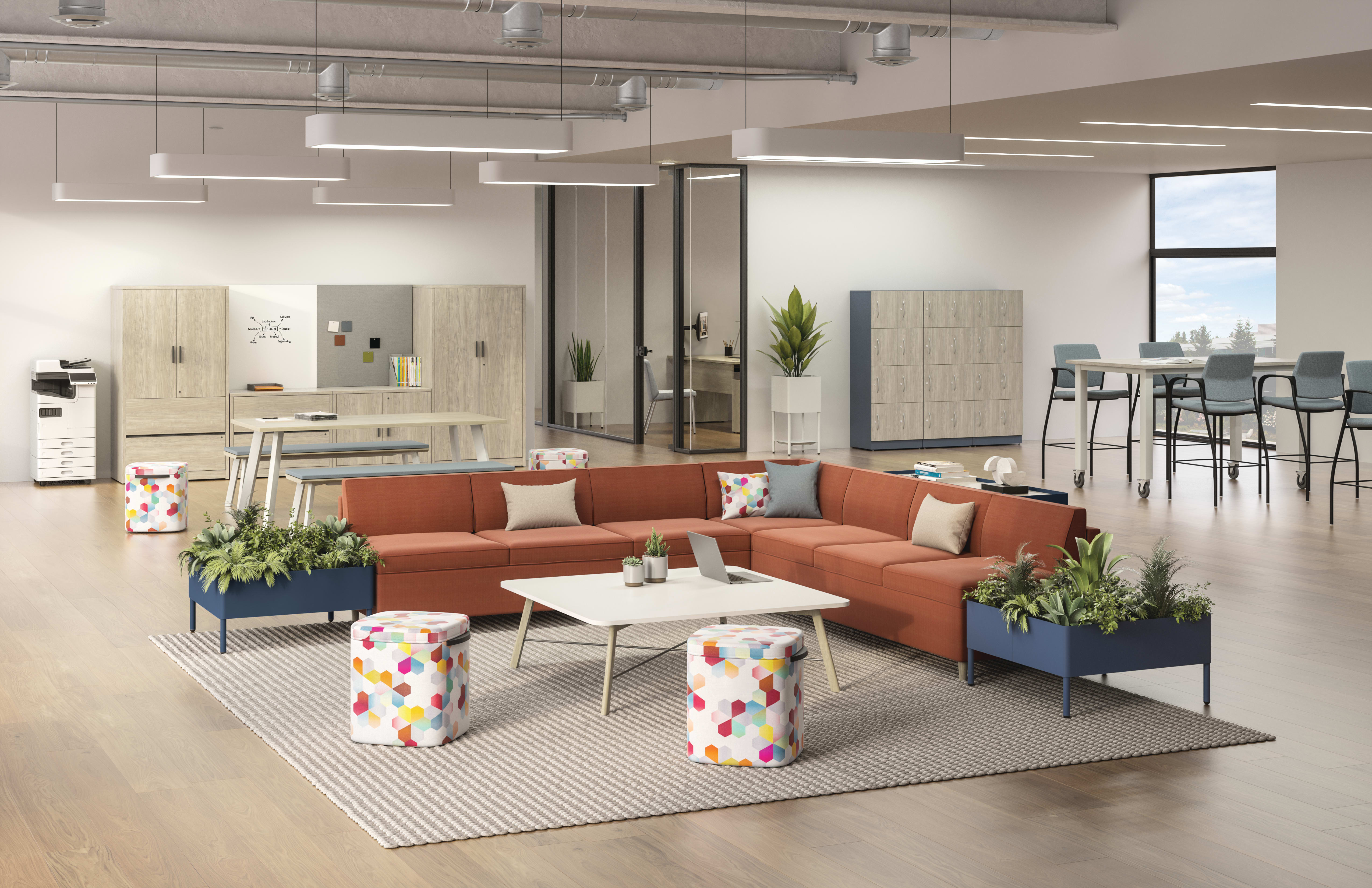 HON West Hill L-shaped sofa centered in a working-lounge with storage, lockers and standing mobile tables. 