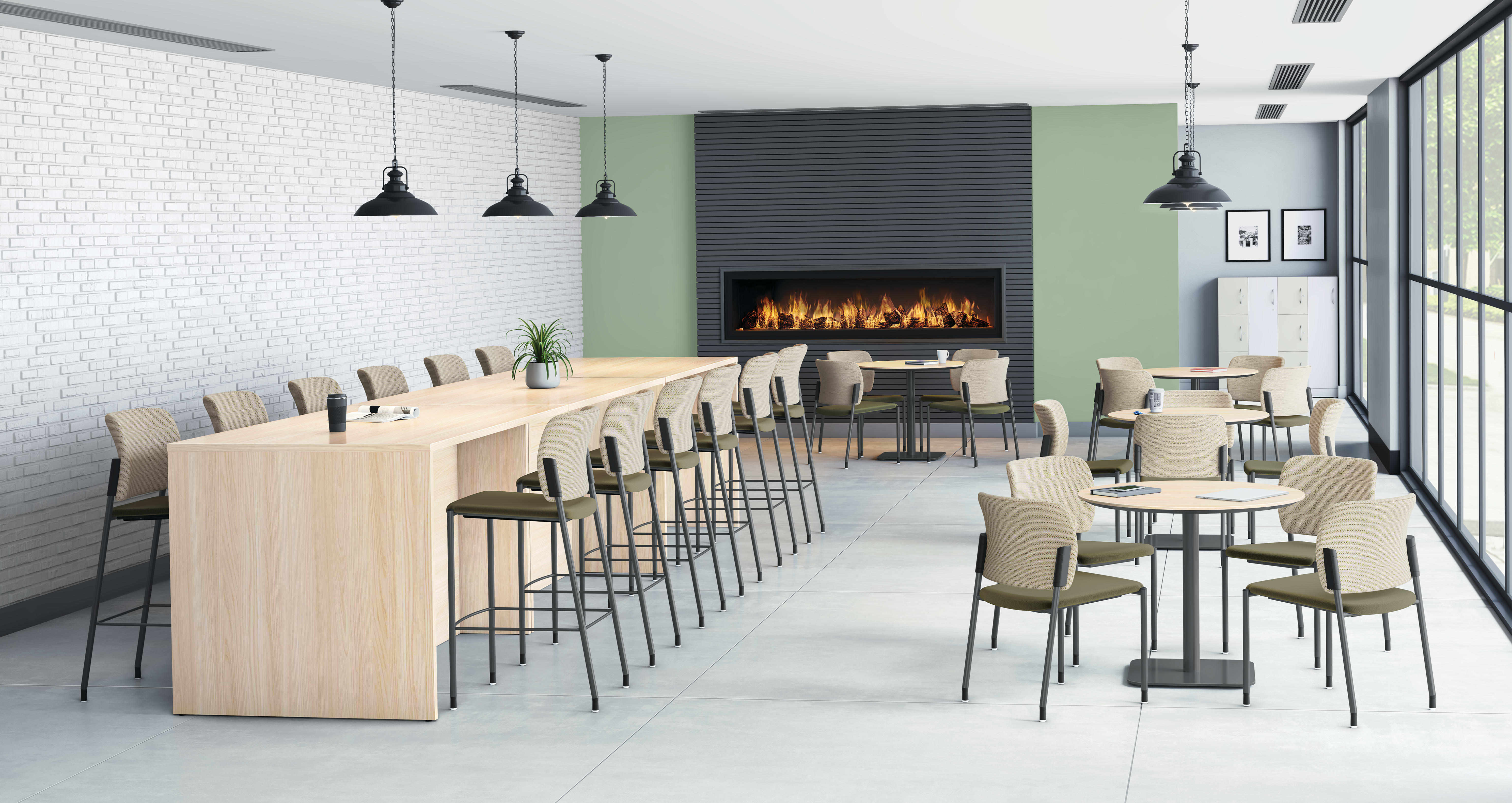 Modern cafeteria with long wooden counter and barstools, round tables with chairs, pendant lights, and built-in fireplace against green and gray accent wall