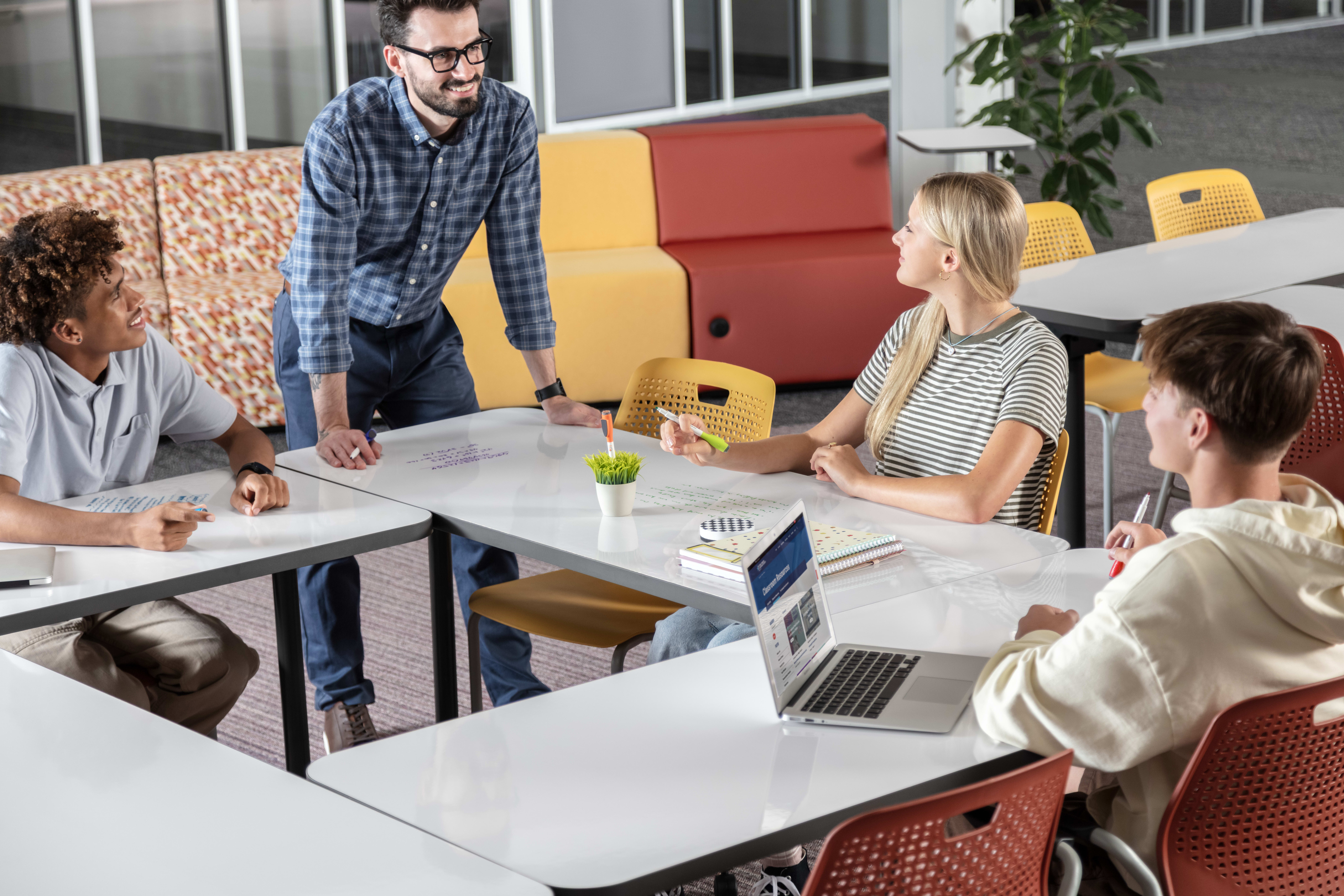 Students and a teacher collaborating in a red and yellow Multi-media Center.