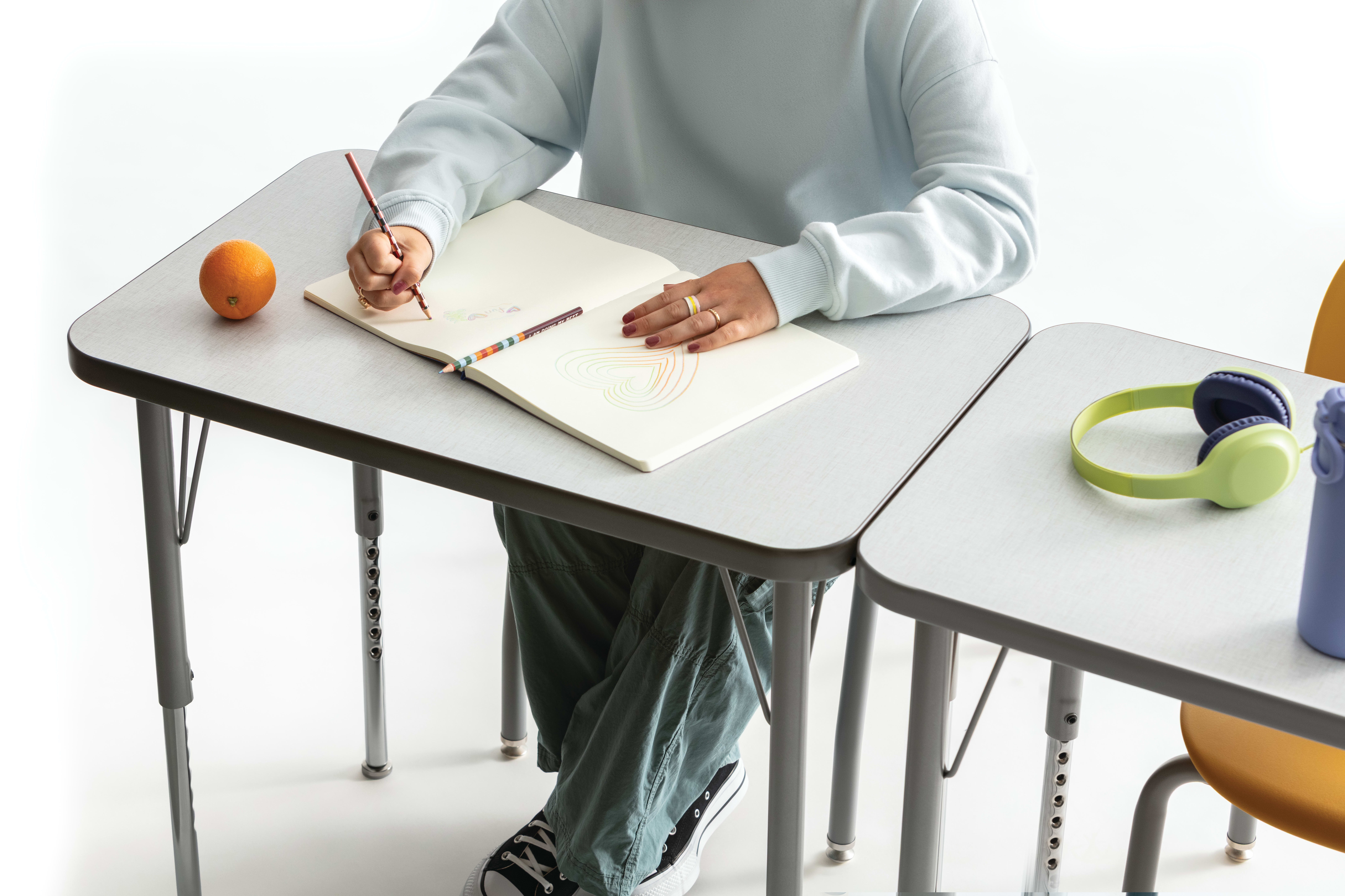 One student writing on the whiteboard top of a Build rectangle top desk.