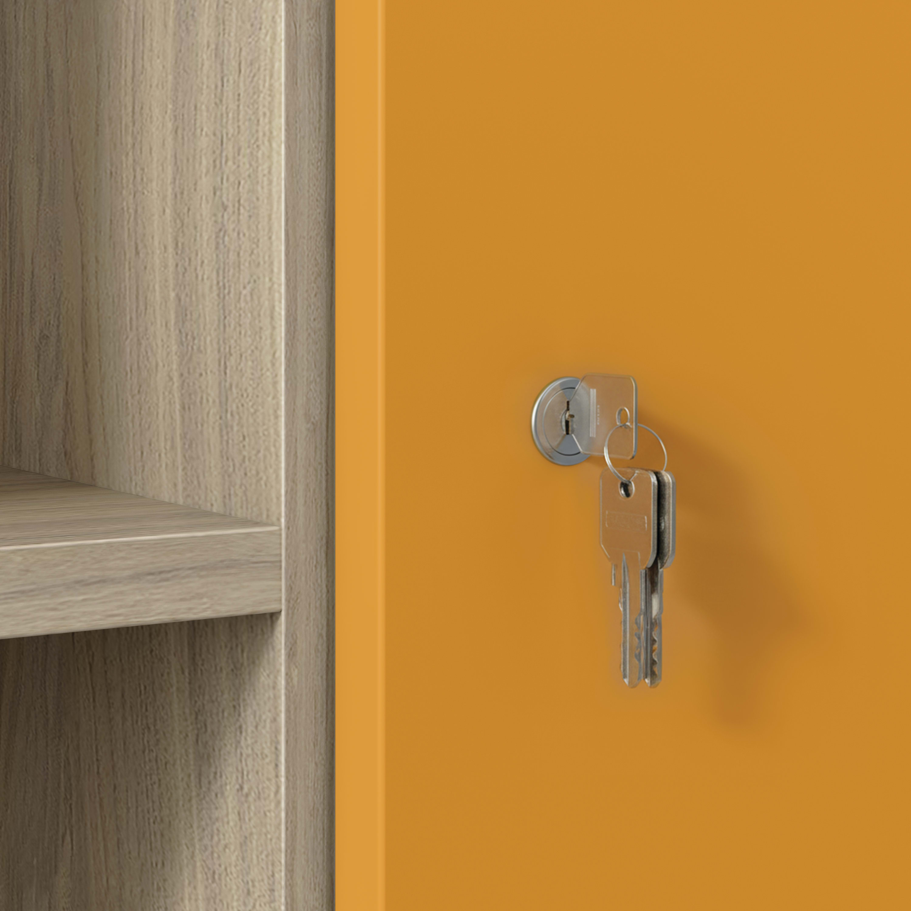 Close-up of silver keys in lock on orange cabinet door with wood shelving.