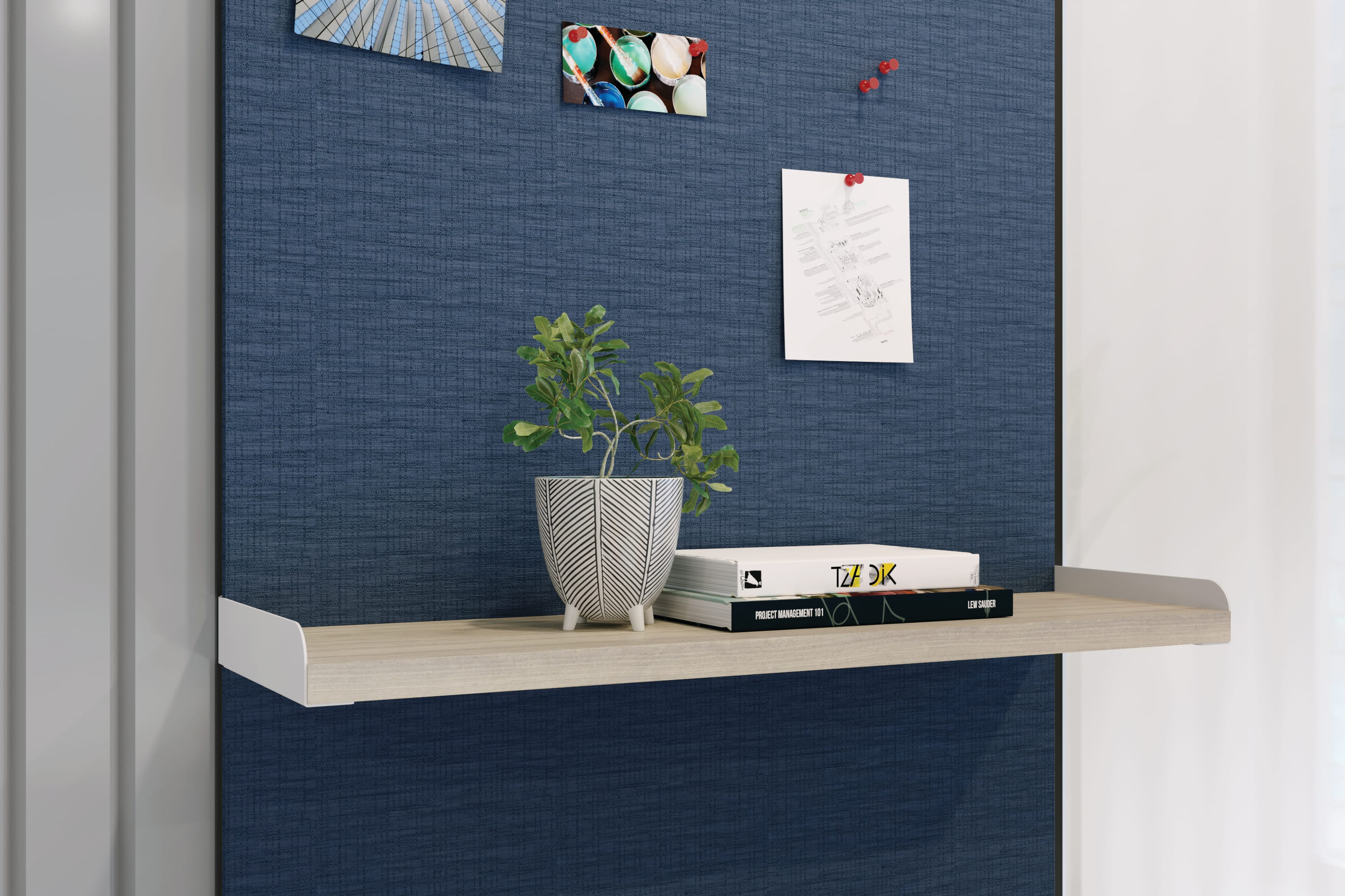 Workwall floating shelf holding small plant and stack of books.