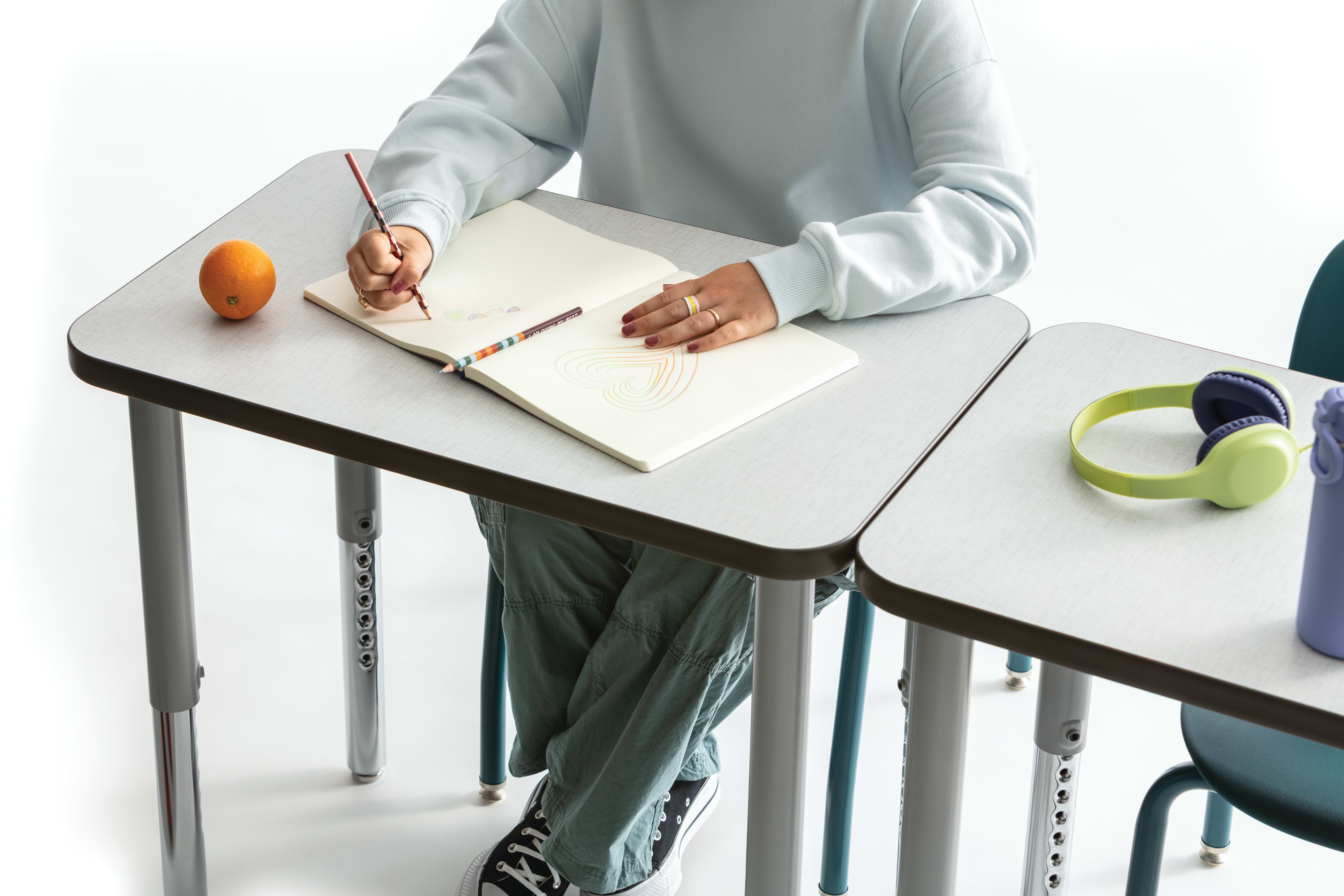 One student writing on the whiteboard top of a Build rectangle top desk.
