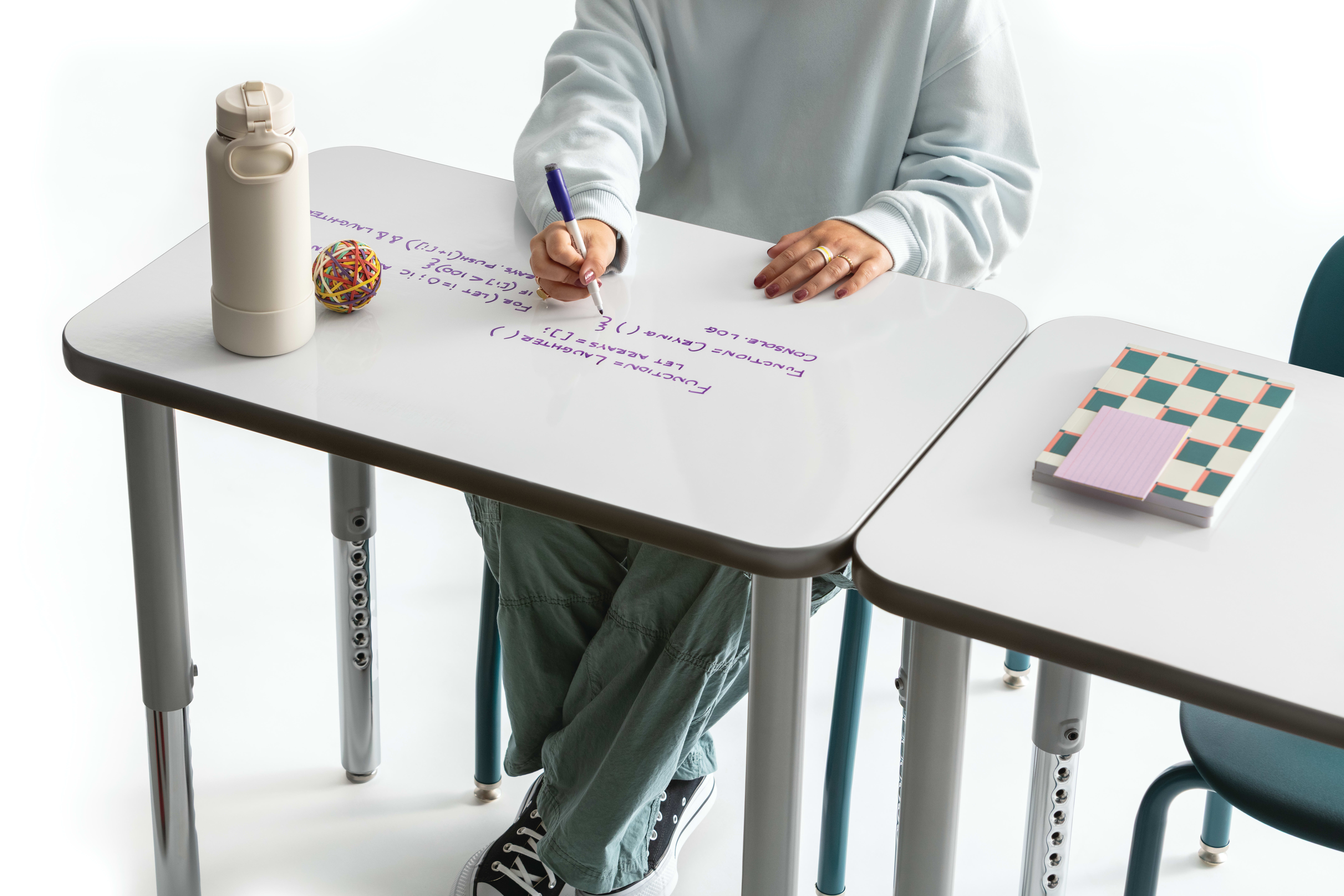 One student writing on the whiteboard top of a Build rectangle top desk.
