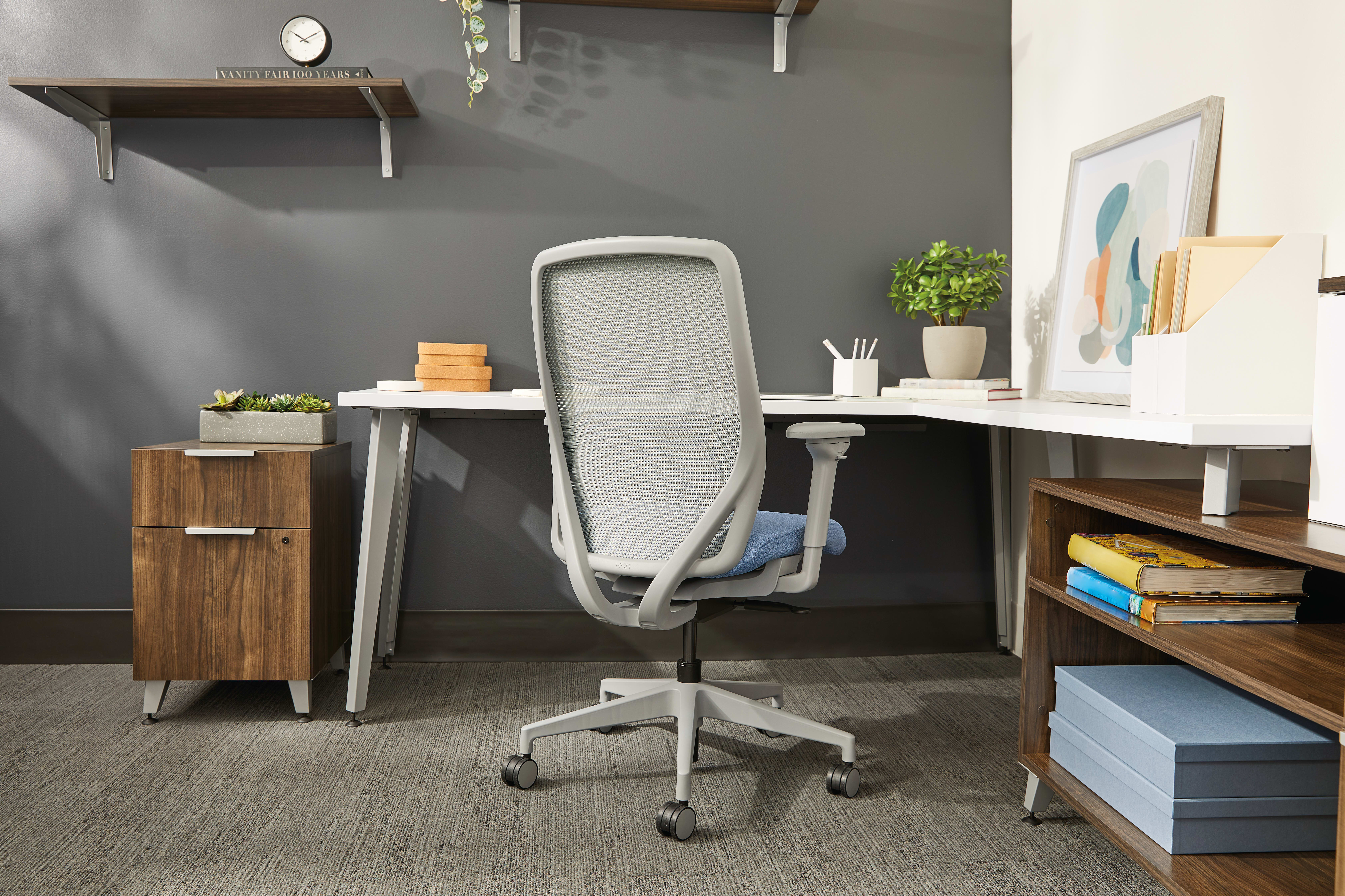 A modern and organized home office space with a comfortable-looking office chair, shelves, and various decorative elements.