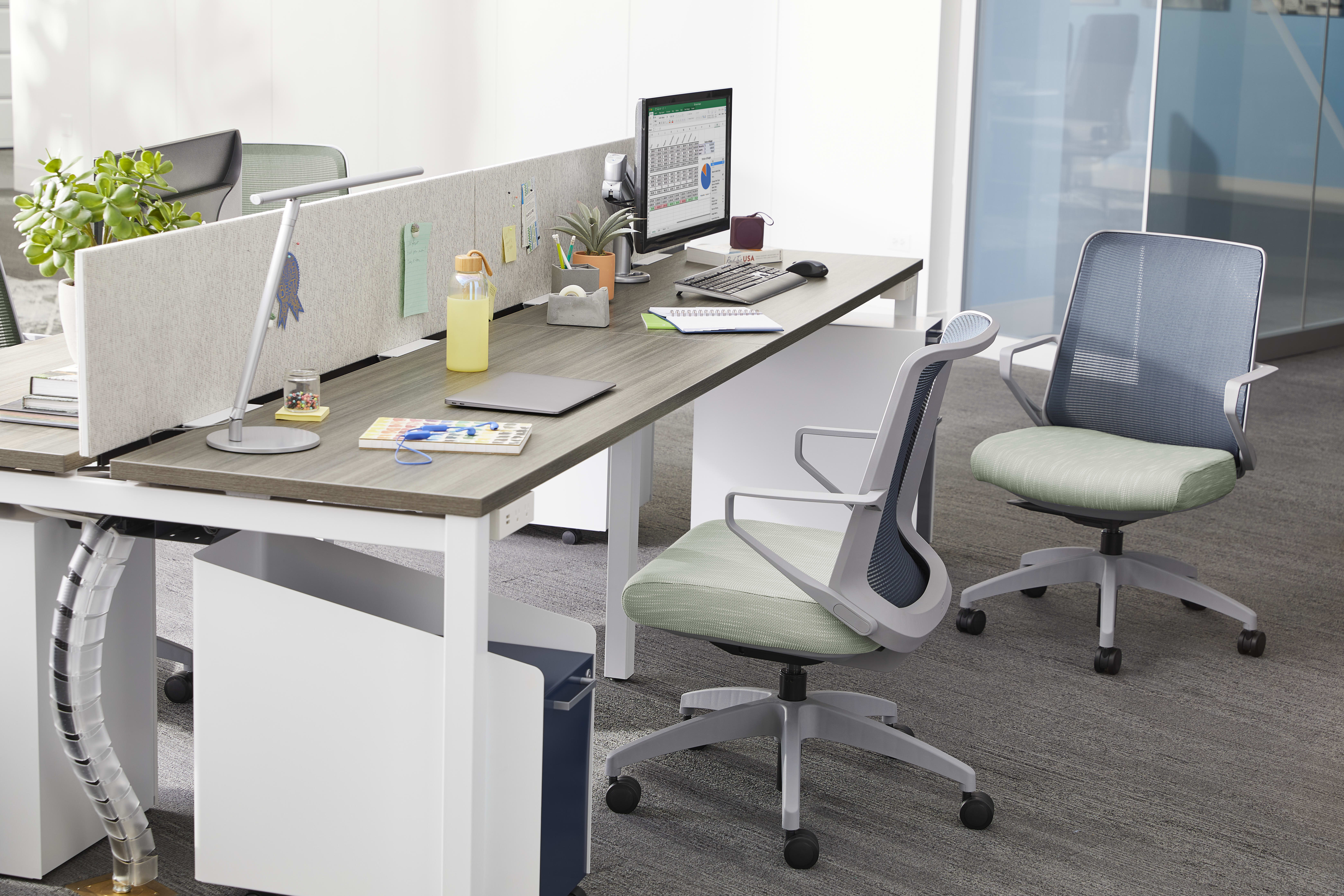 A modern, minimalist office workspace with a desk, computer, and various office supplies and accessories, set against a plain white wall background.