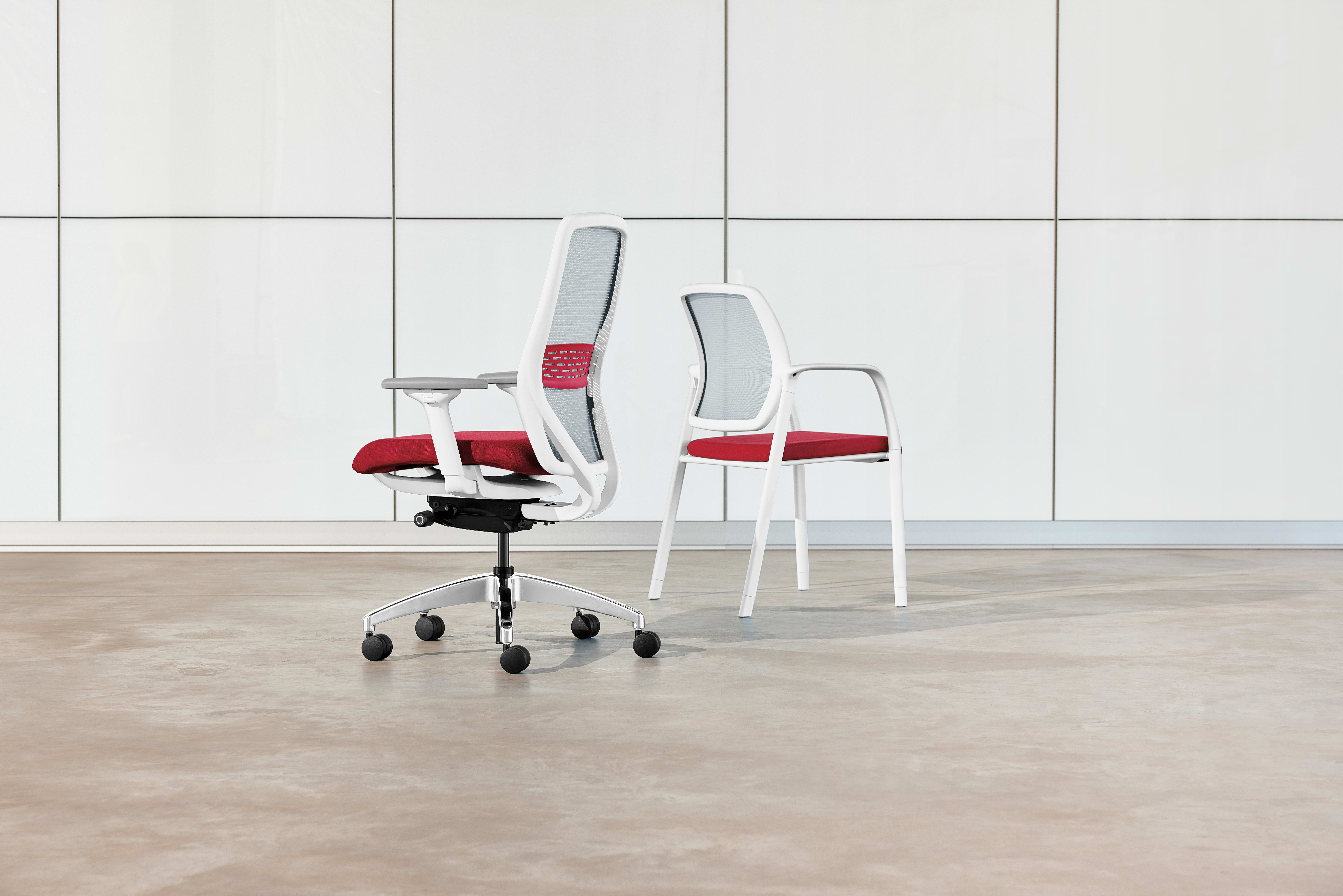 The image shows a modern office chair and two matching chairs in a minimalist, white-tiled room.