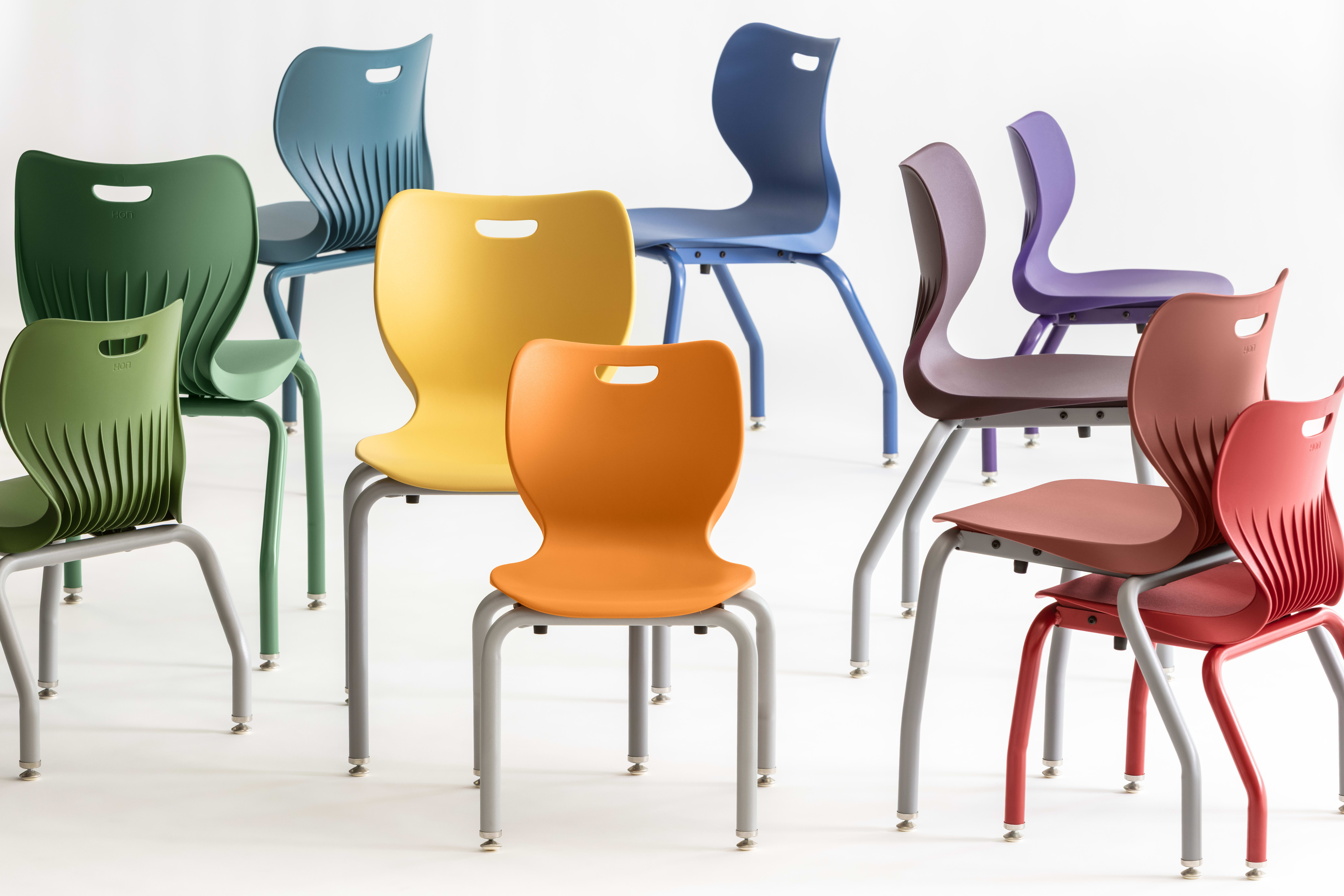 A collection of colorful, modern chairs in various shades of green, blue, yellow, and red, arranged against a plain white background.