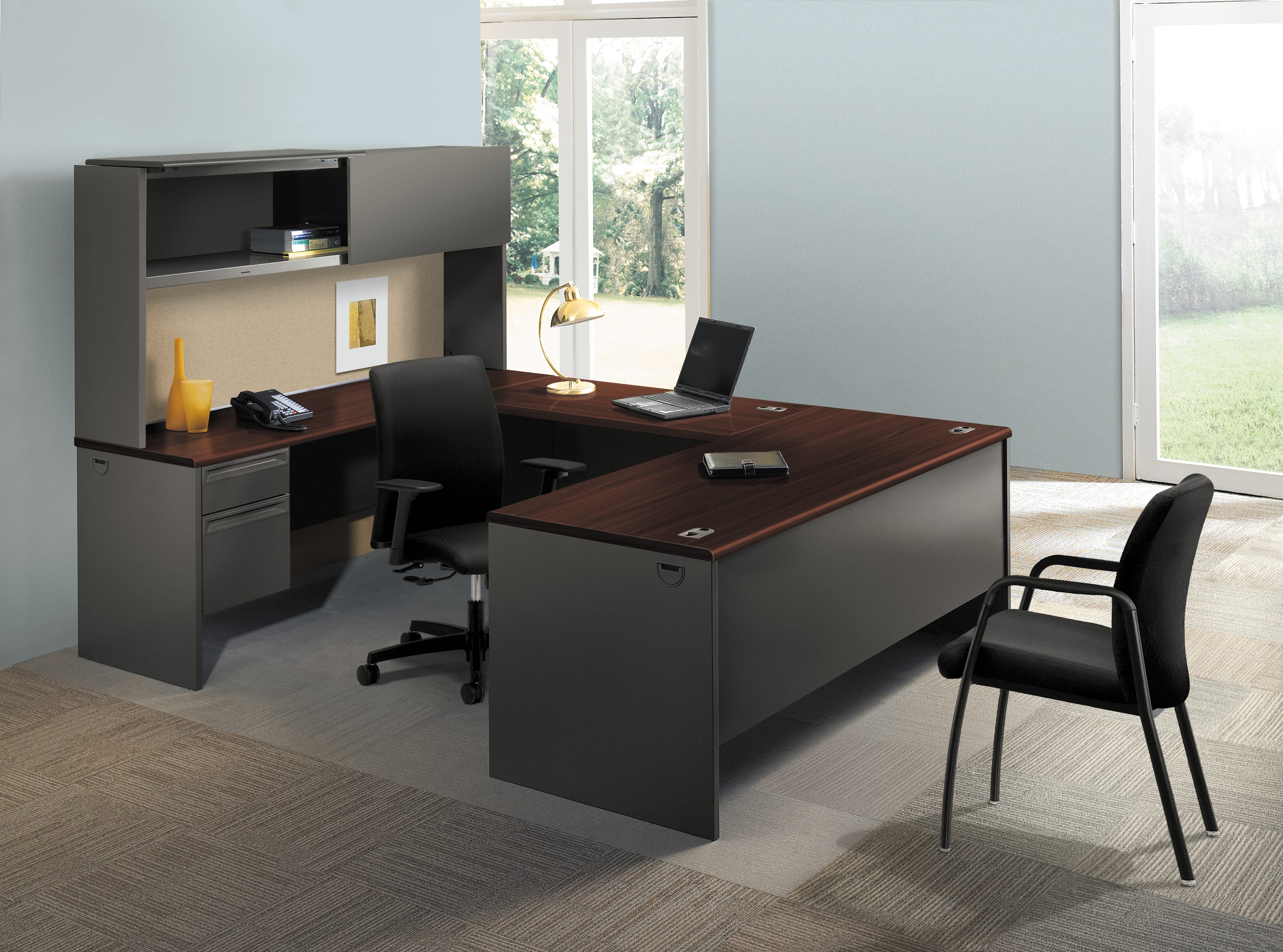 A modern and minimalist home office setup with a large wooden desk, a black office chair, and a storage unit with shelves and drawers, all set against a bright and airy background with a large window overlooking the outdoors.