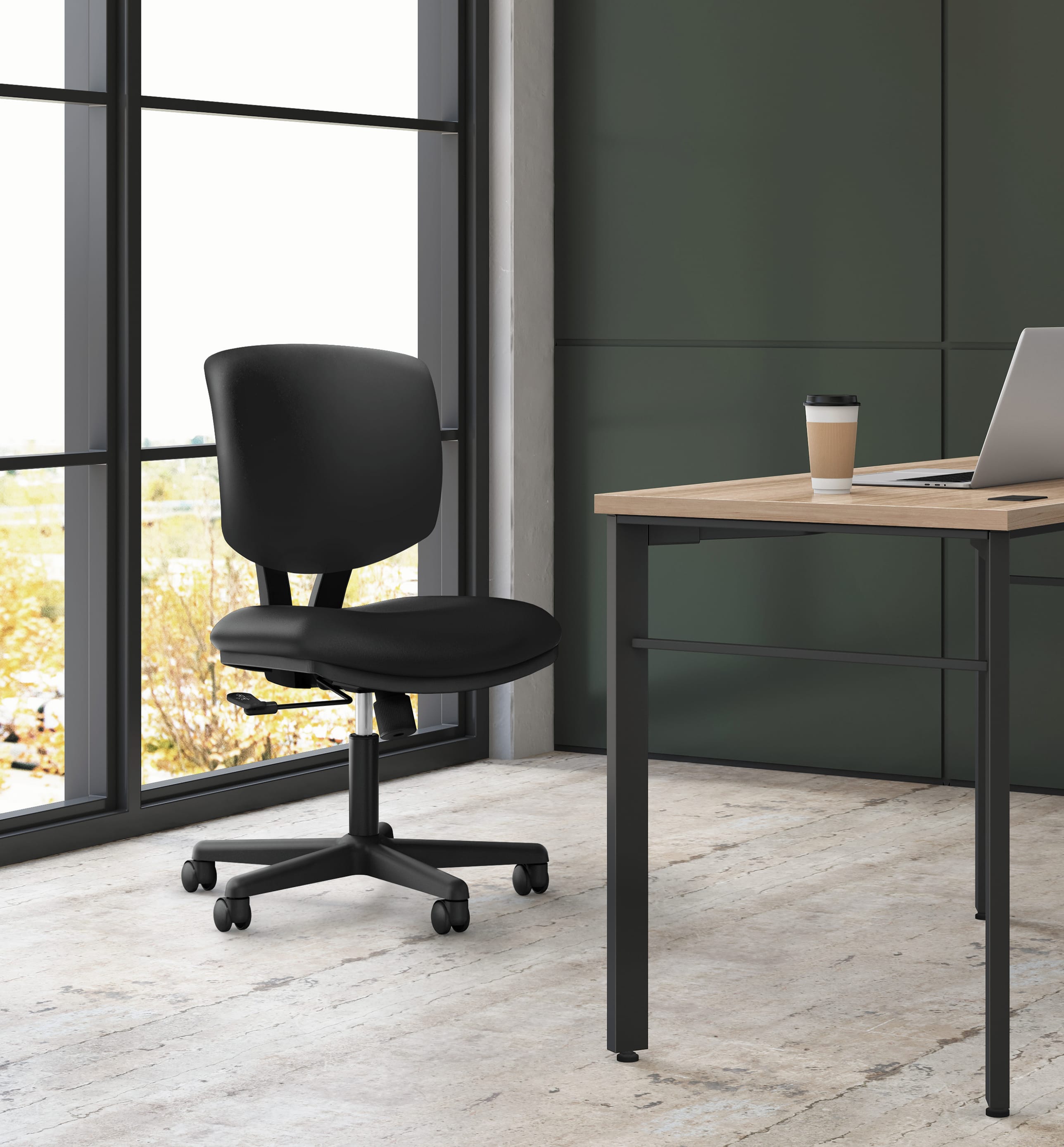 A modern, minimalist office space with a black office chair and a wooden desk near a large window overlooking a natural landscape.