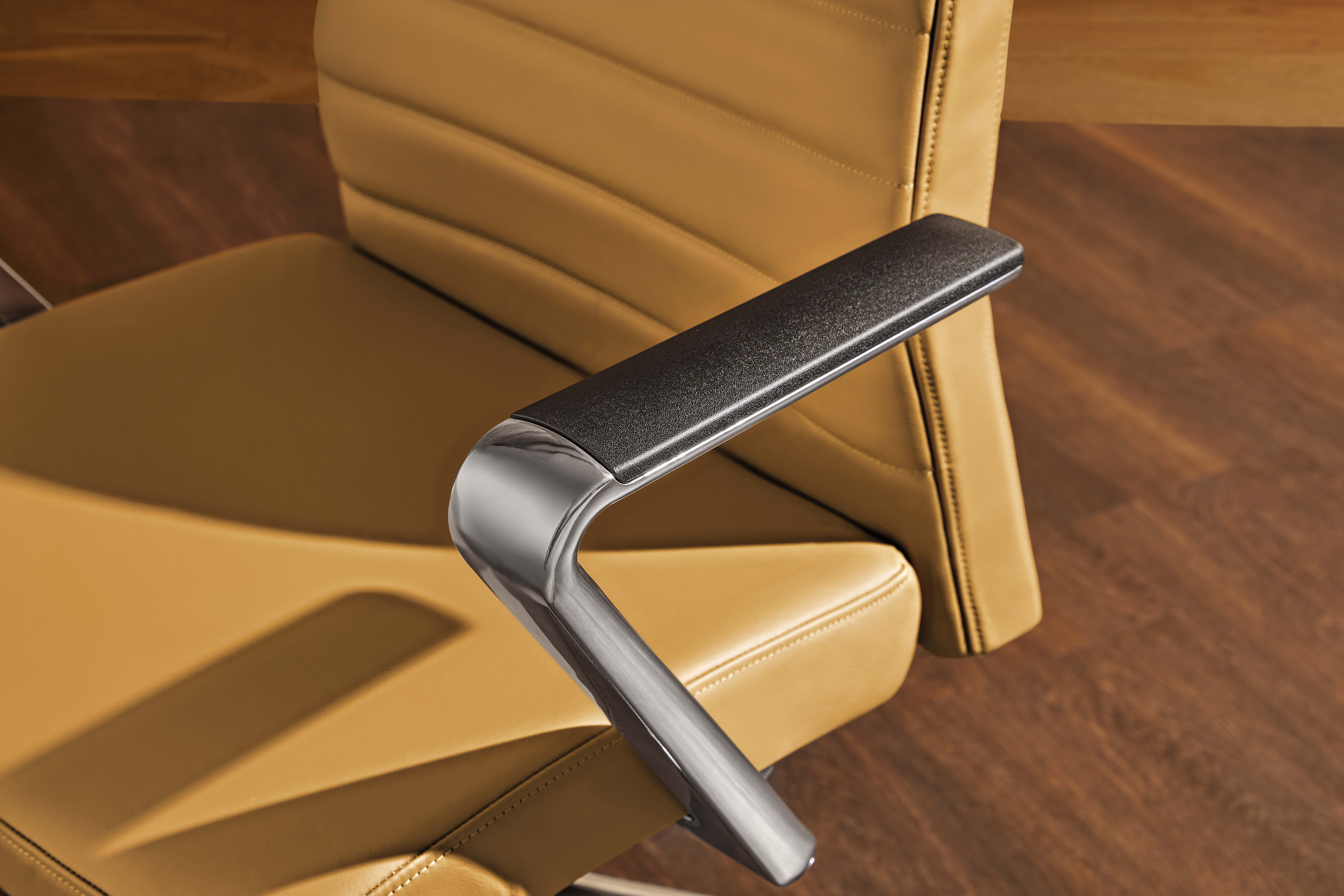 The image shows a close-up view of a chair's armrest, featuring a sleek and modern design with a black padded surface and a metallic frame.