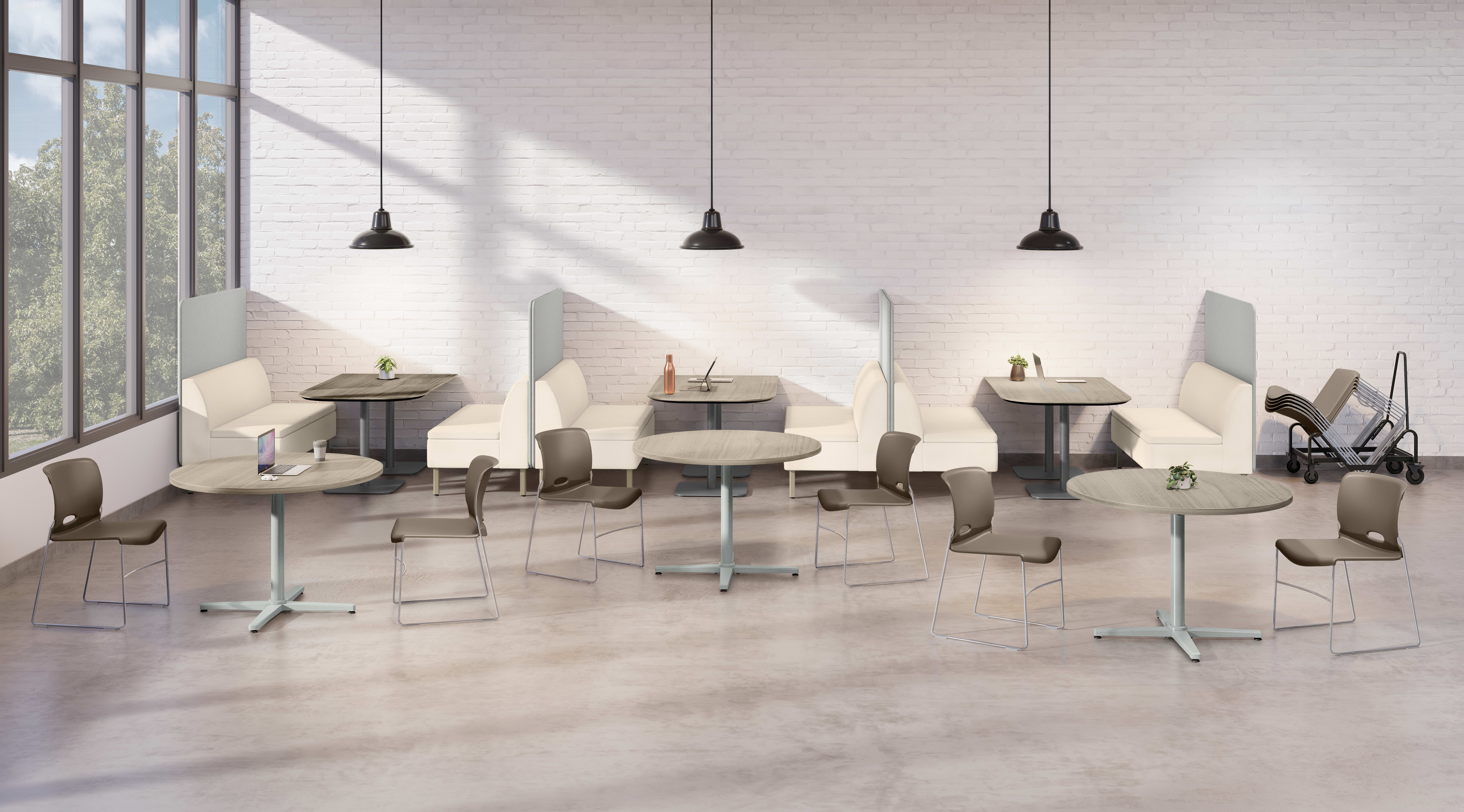 An open dining area with round tables, chairs, booth seating, hanging pendant lights, and large windows allowing natural light into the space.