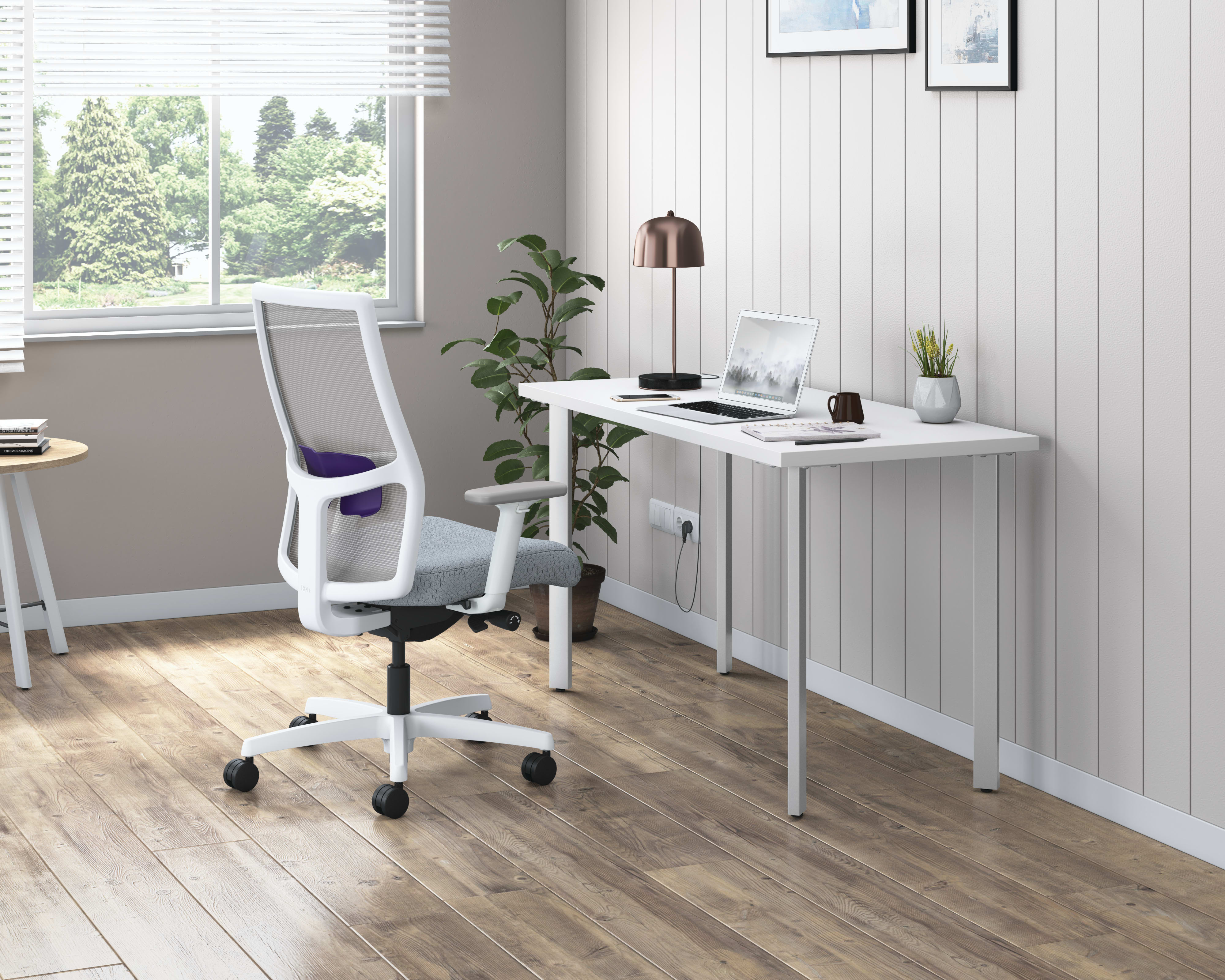 A modern and minimalist home office space with a white desk, a comfortable office chair, and a large window overlooking a lush outdoor landscape.