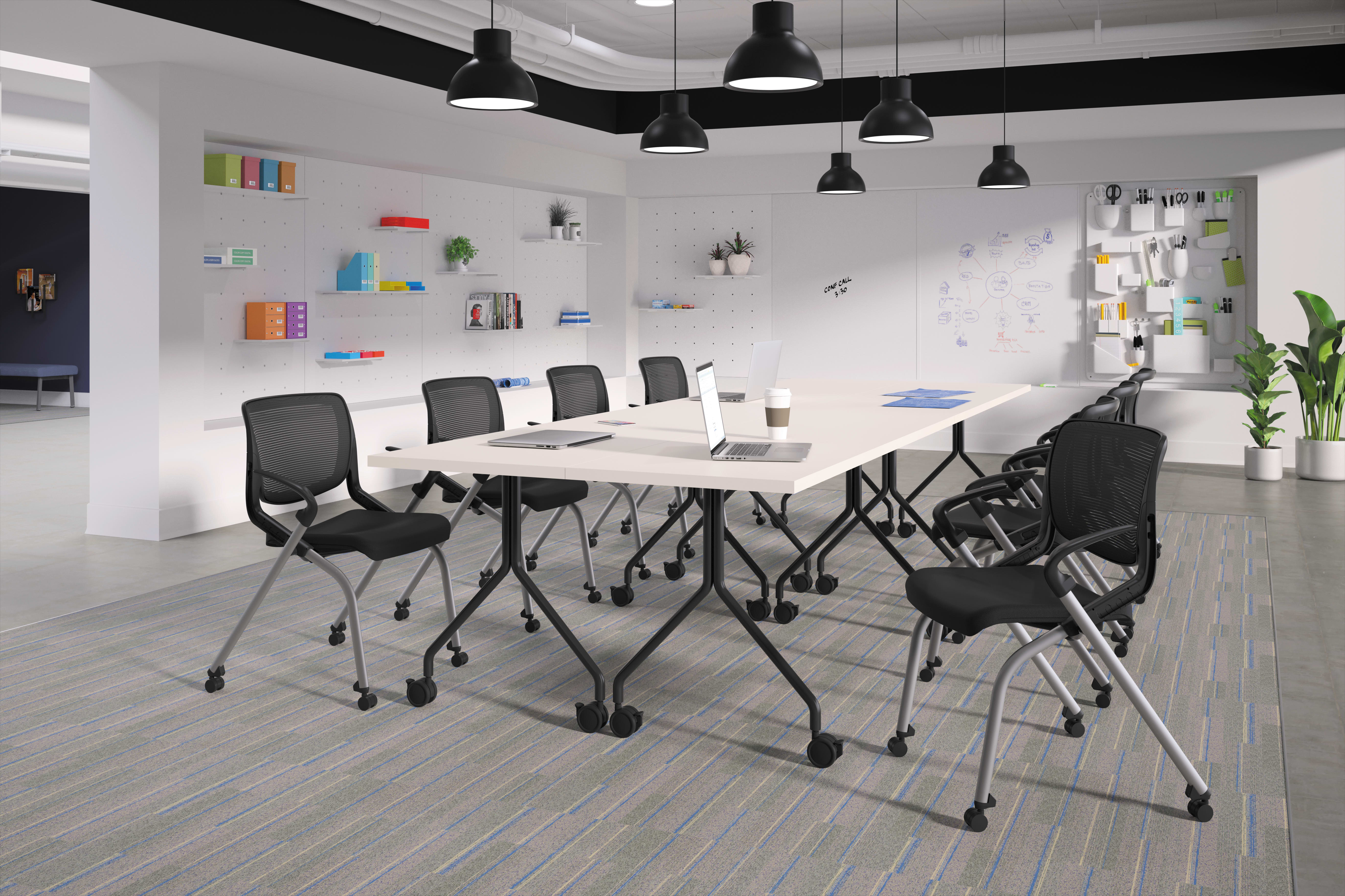 A modern and minimalist office space with a long table, black chairs, and various shelves and decor elements on the walls.