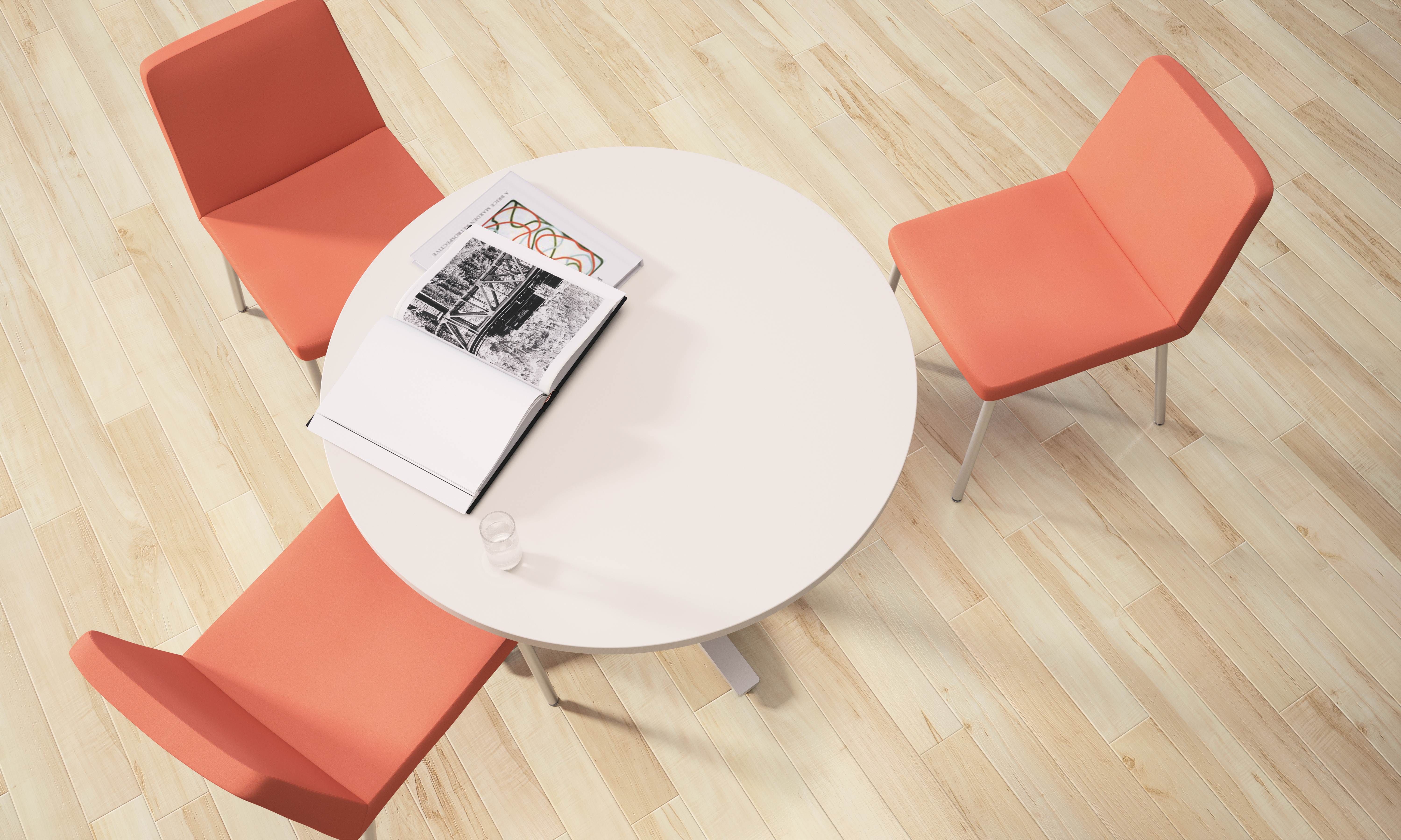 A round white table with a magazine on it, surrounded by four orange chairs on a wooden floor.