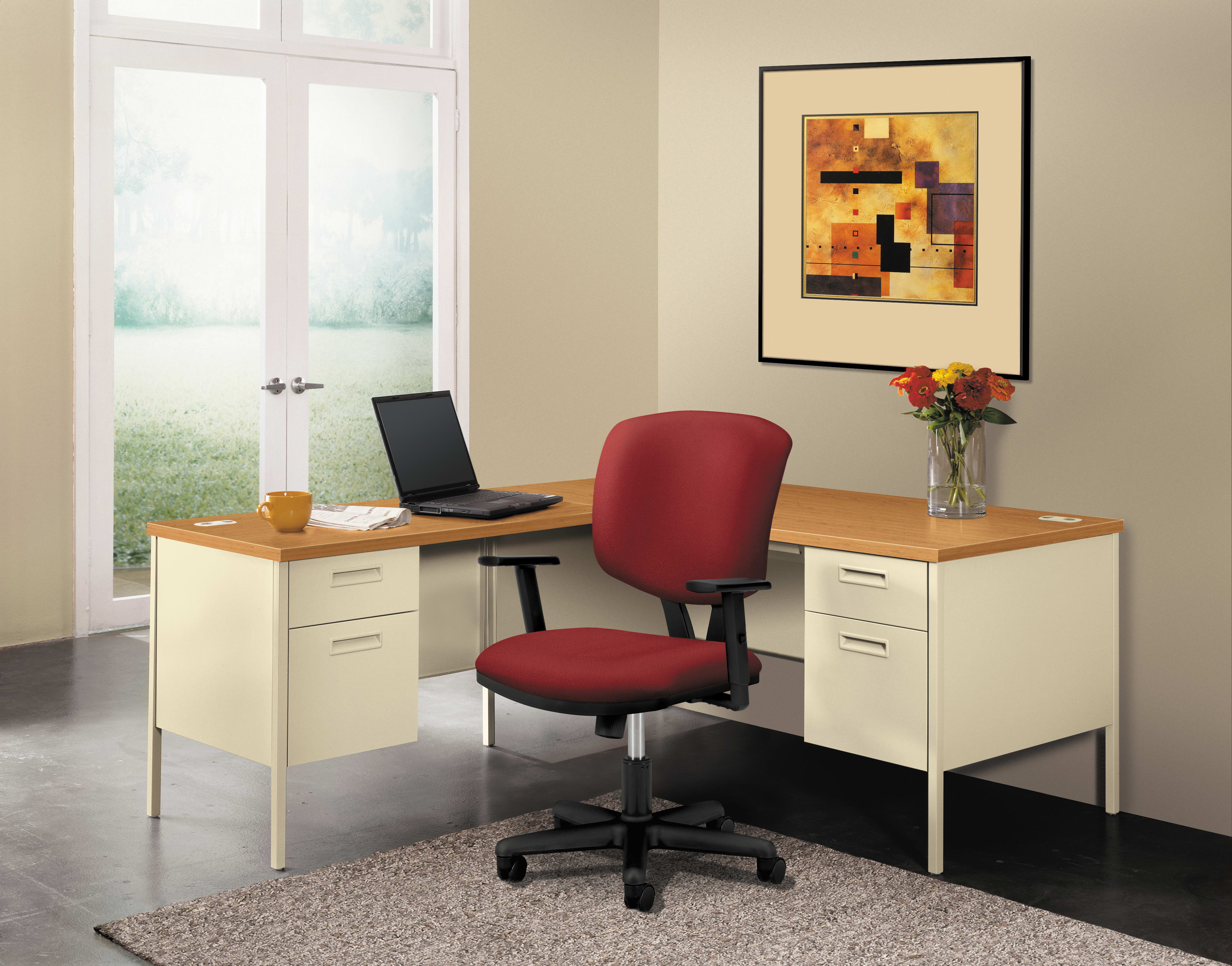 A modern home office with a wooden desk, a red office chair, and a framed abstract artwork on the wall, set against a backdrop of a large window overlooking a scenic outdoor view.
