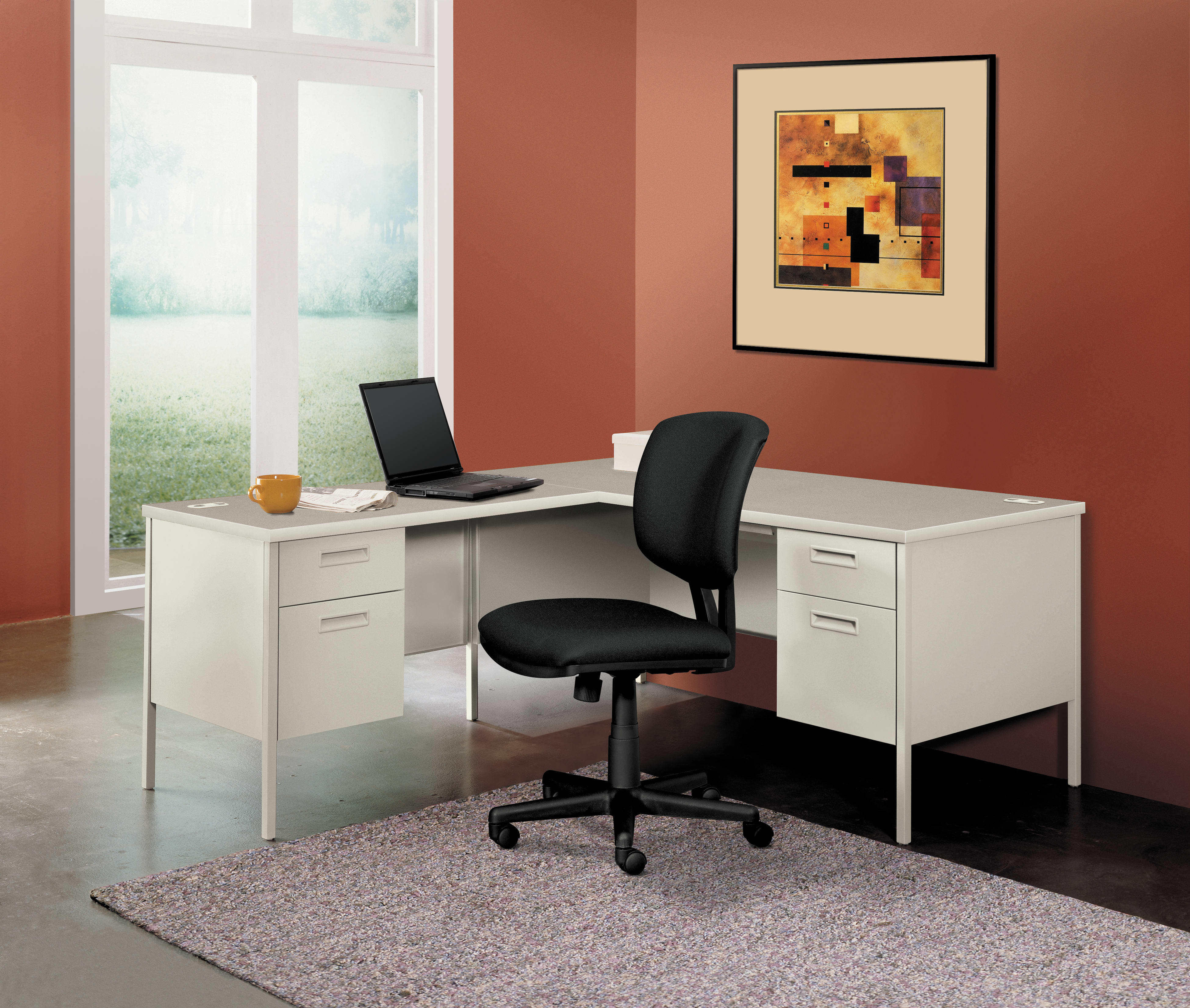 A modern home office setup with a white desk, a black office chair, and a framed abstract artwork on the wall, set against a warm-toned wall color.