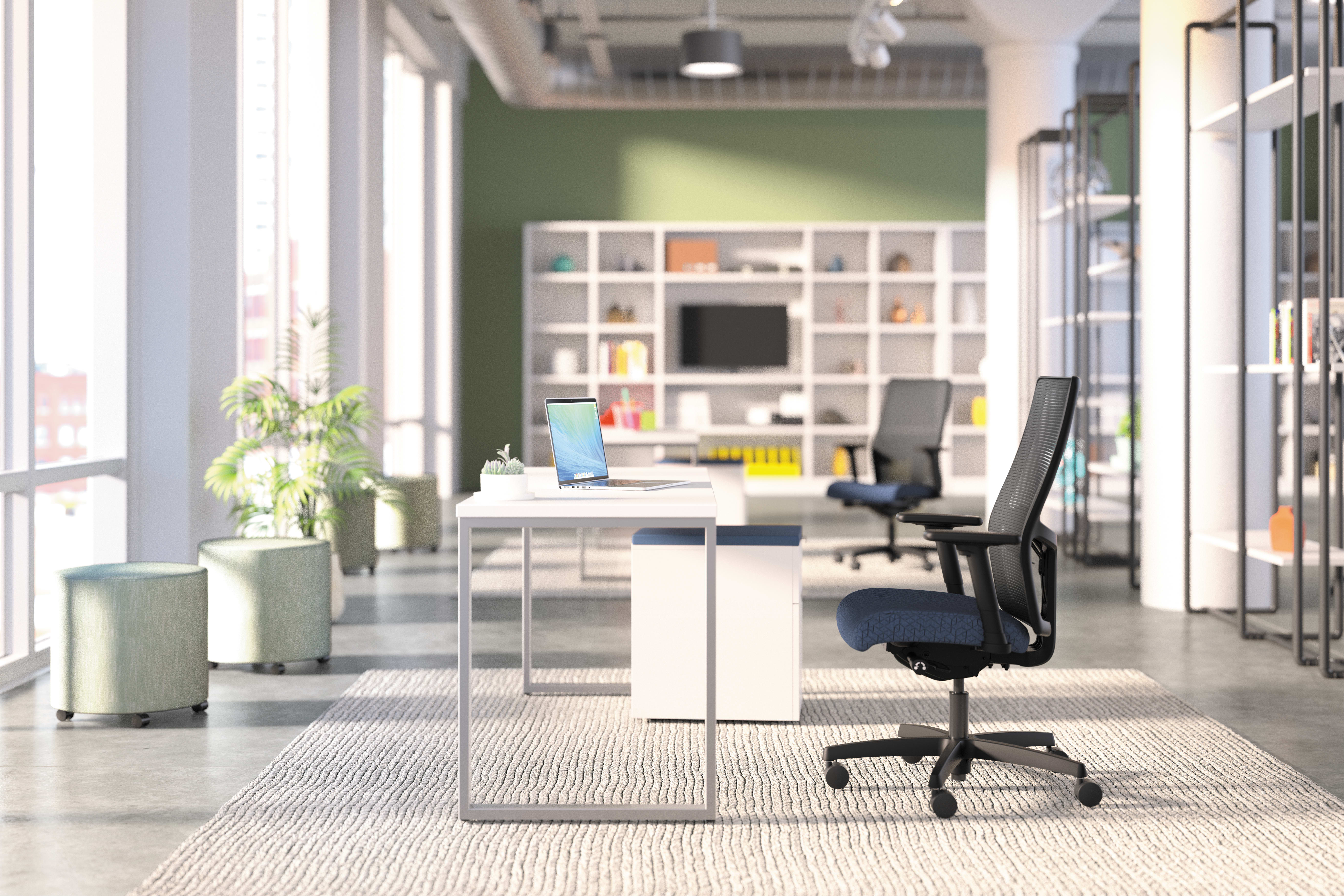 A modern, open-concept office space with a desk, chair, and shelving unit in the foreground, and a plant and other decor elements in the background, creating a bright and organized work environment.