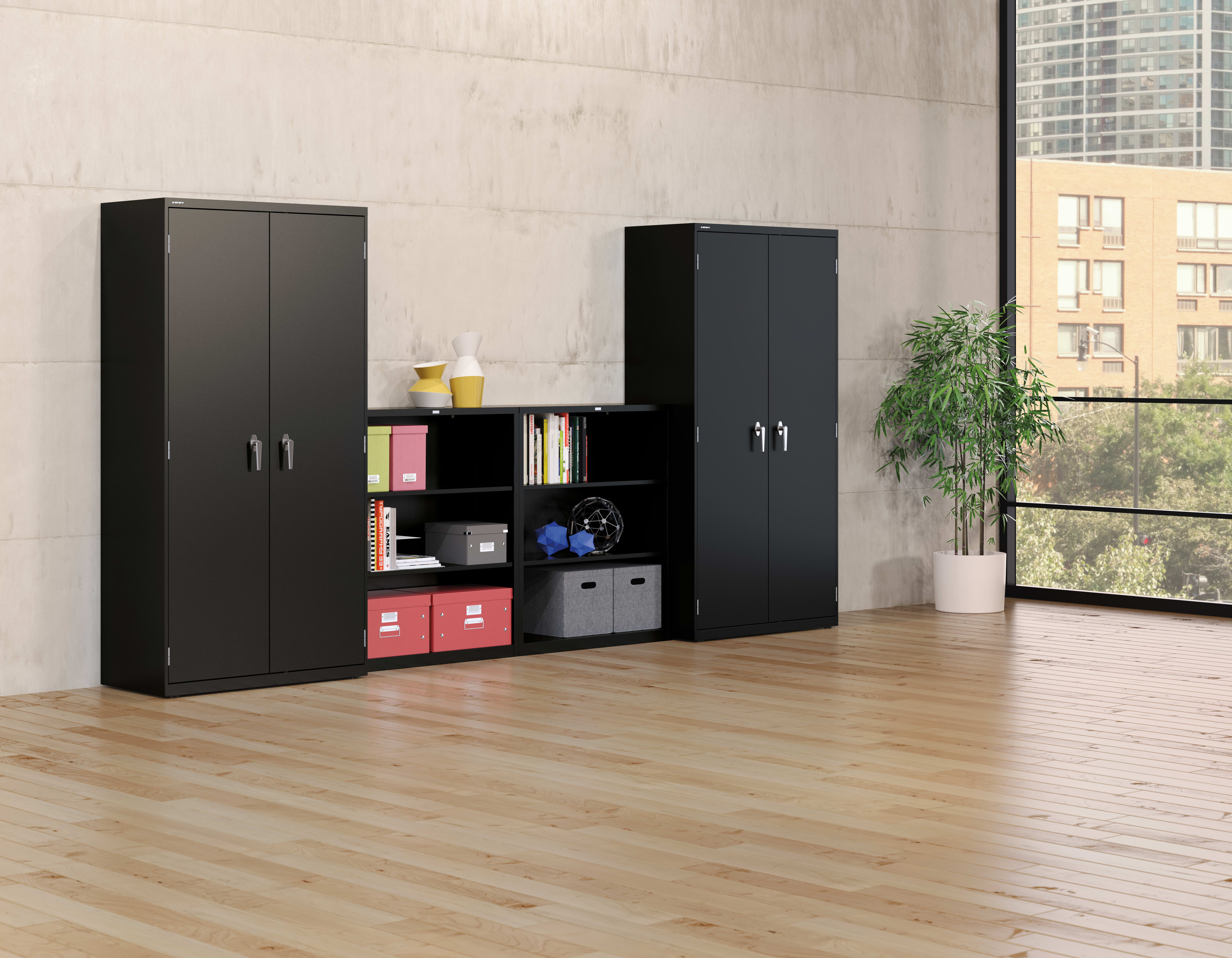 The image depicts a modern and minimalist home office or study space, featuring two black storage cabinets with shelves and compartments, a potted plant, and a large window overlooking a cityscape in the background.