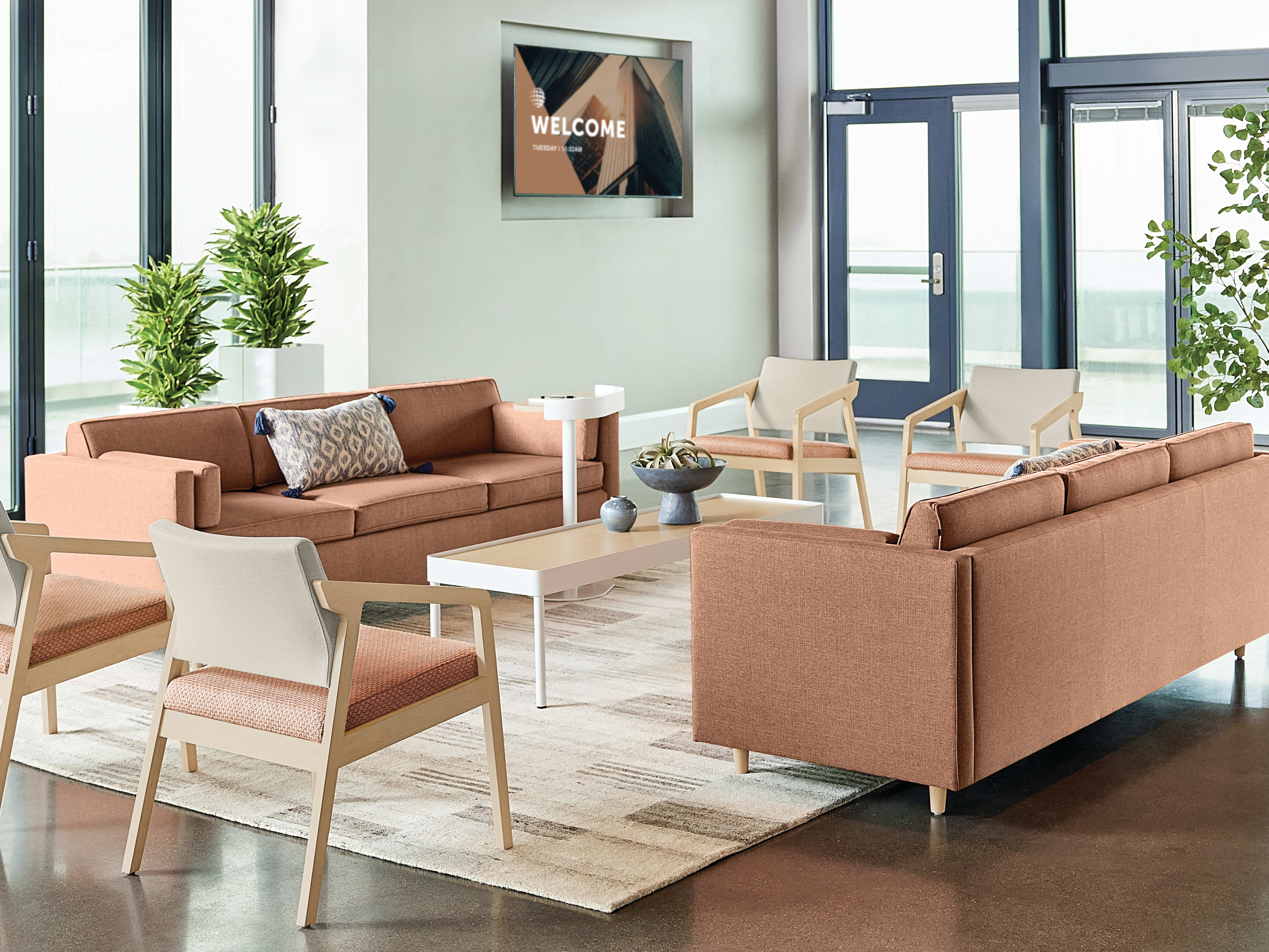 A modern and inviting lobby area with comfortable seating arrangements, potted plants, and a welcoming sign on the wall.