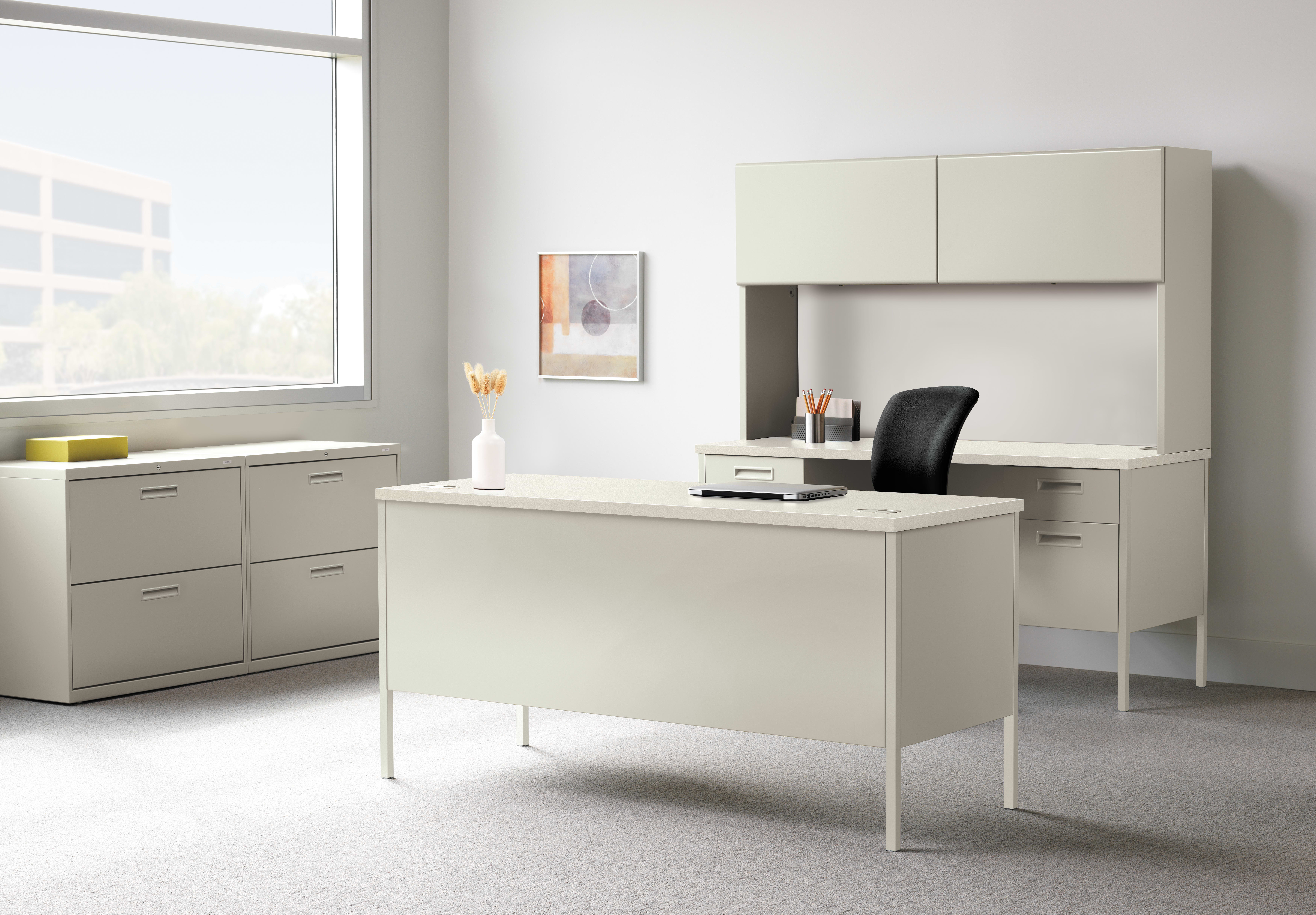 A modern, minimalist office space with a white desk, cabinets, and a framed artwork on the wall, set against a bright, natural light-filled background.