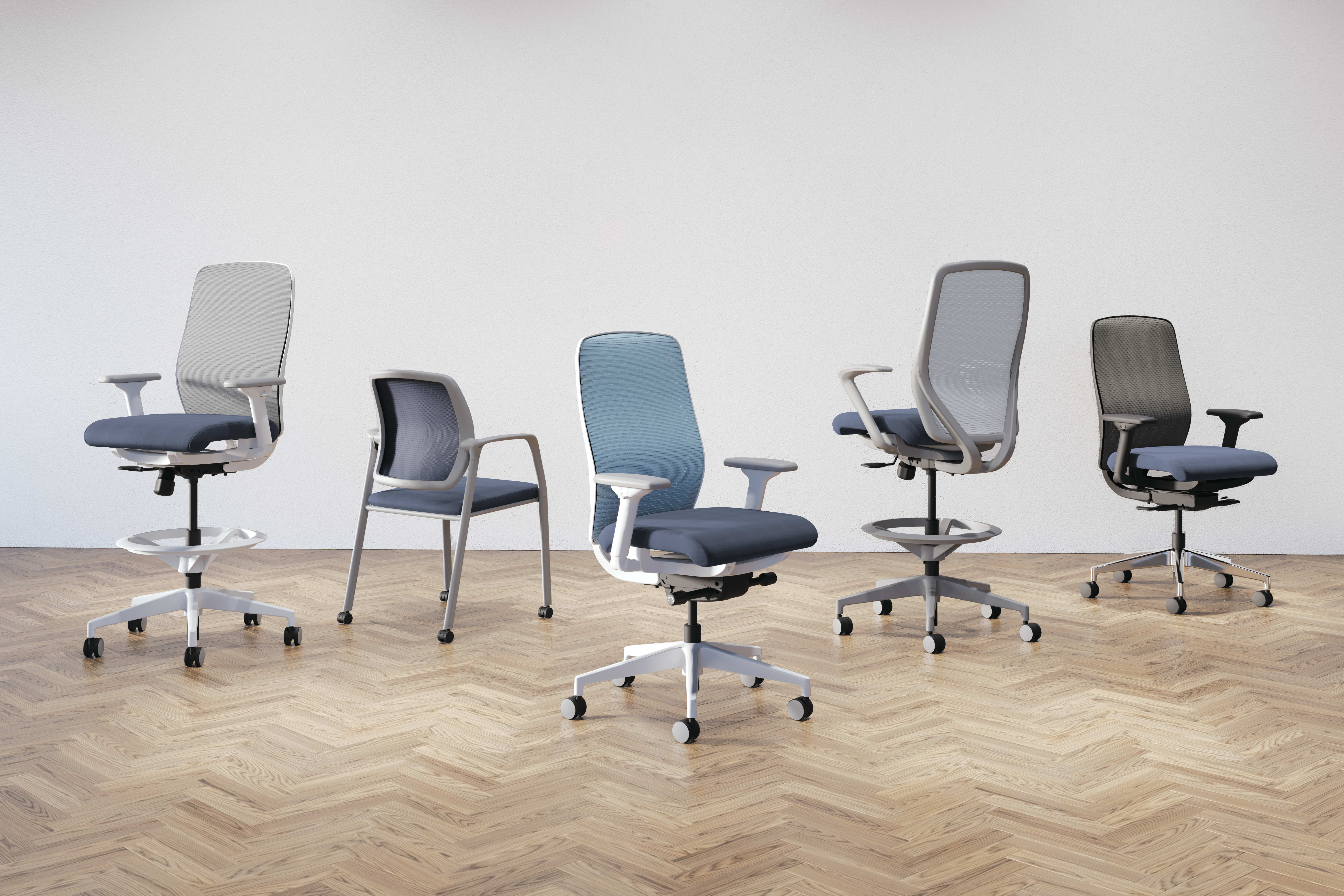 A collection of modern, adjustable office chairs in various shades of gray and blue, arranged on a herringbone-patterned wooden floor against a plain background.