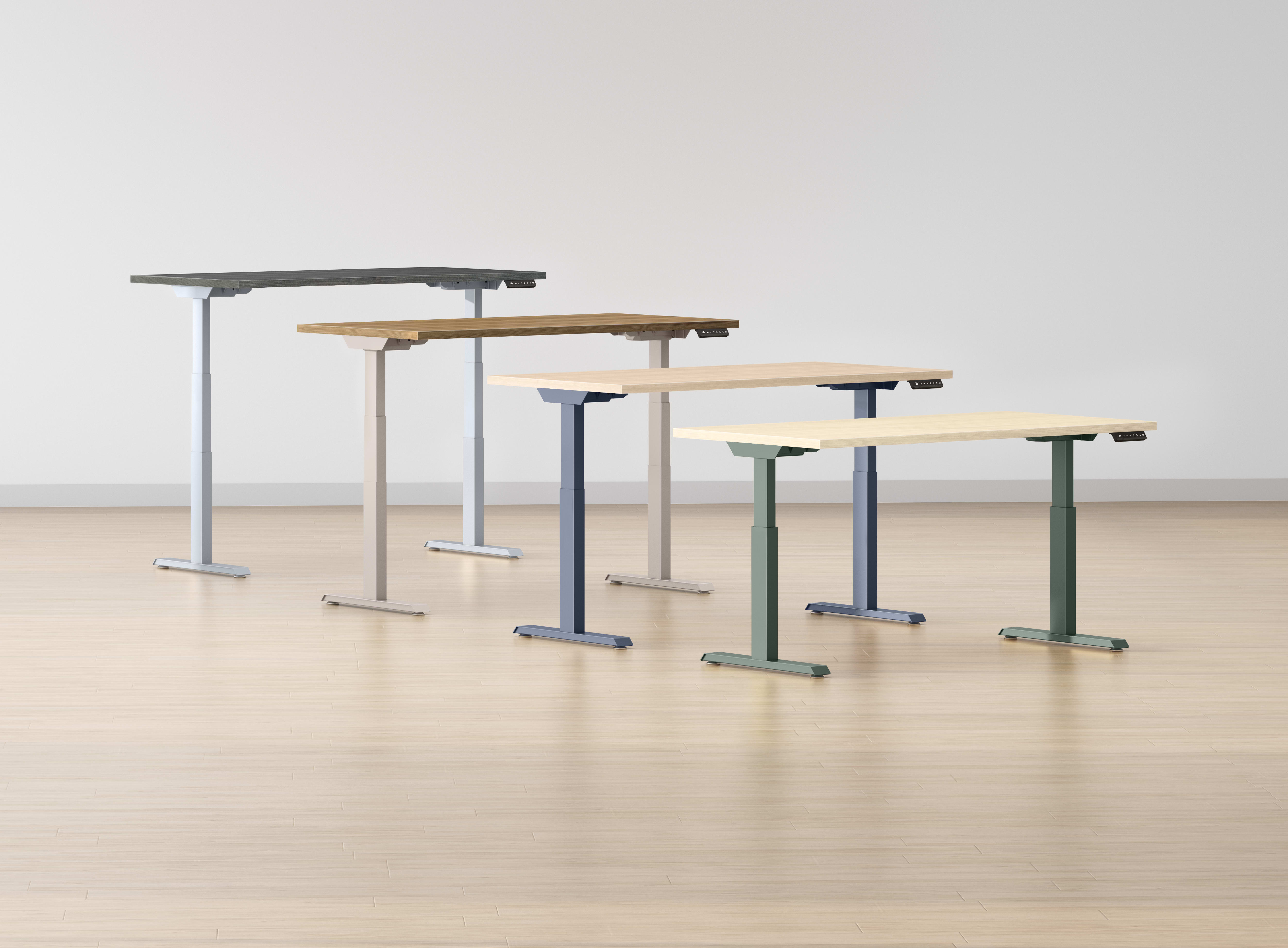A collection of adjustable standing desks or workstations in various sizes and colors, arranged on a wooden floor against a plain white background.