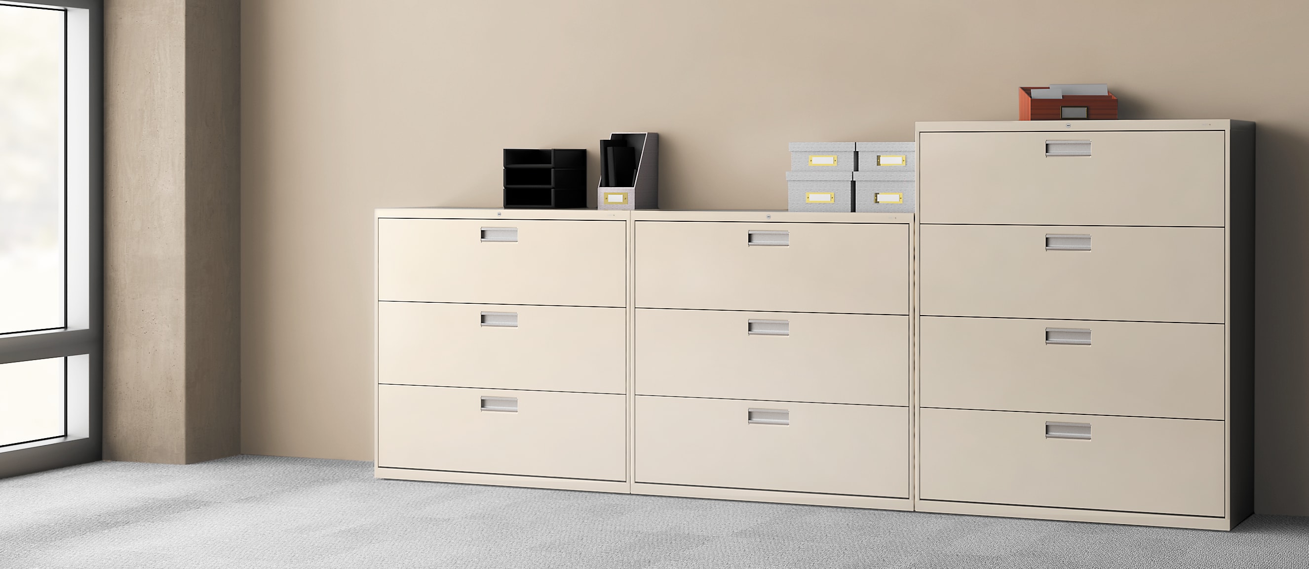 The image depicts a set of white filing cabinets in a minimalist office setting, with various office supplies and equipment visible in the background.