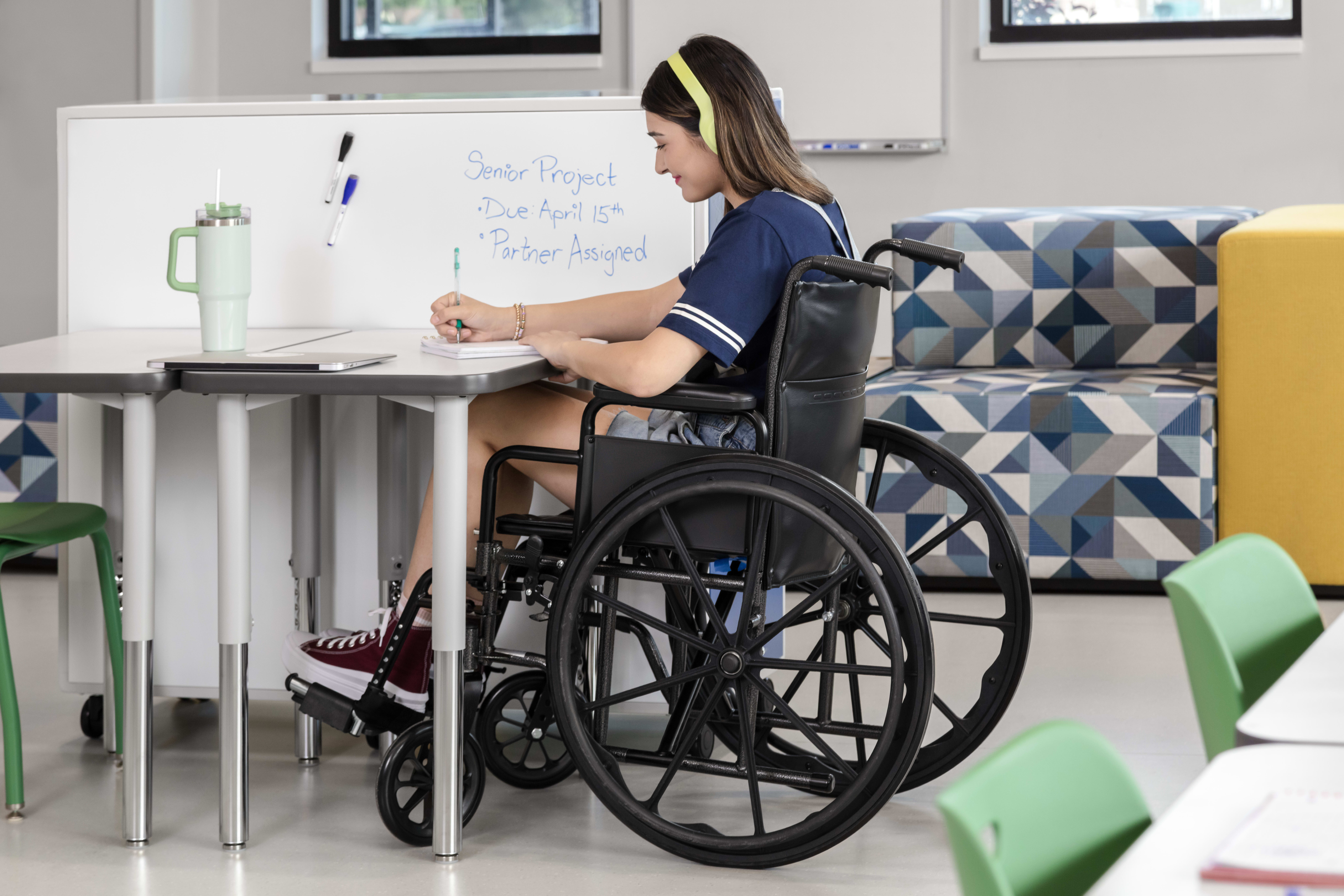 One student in a wheelchair at a Build desk next to the whiteboard back of a Class-ifi storage unit.