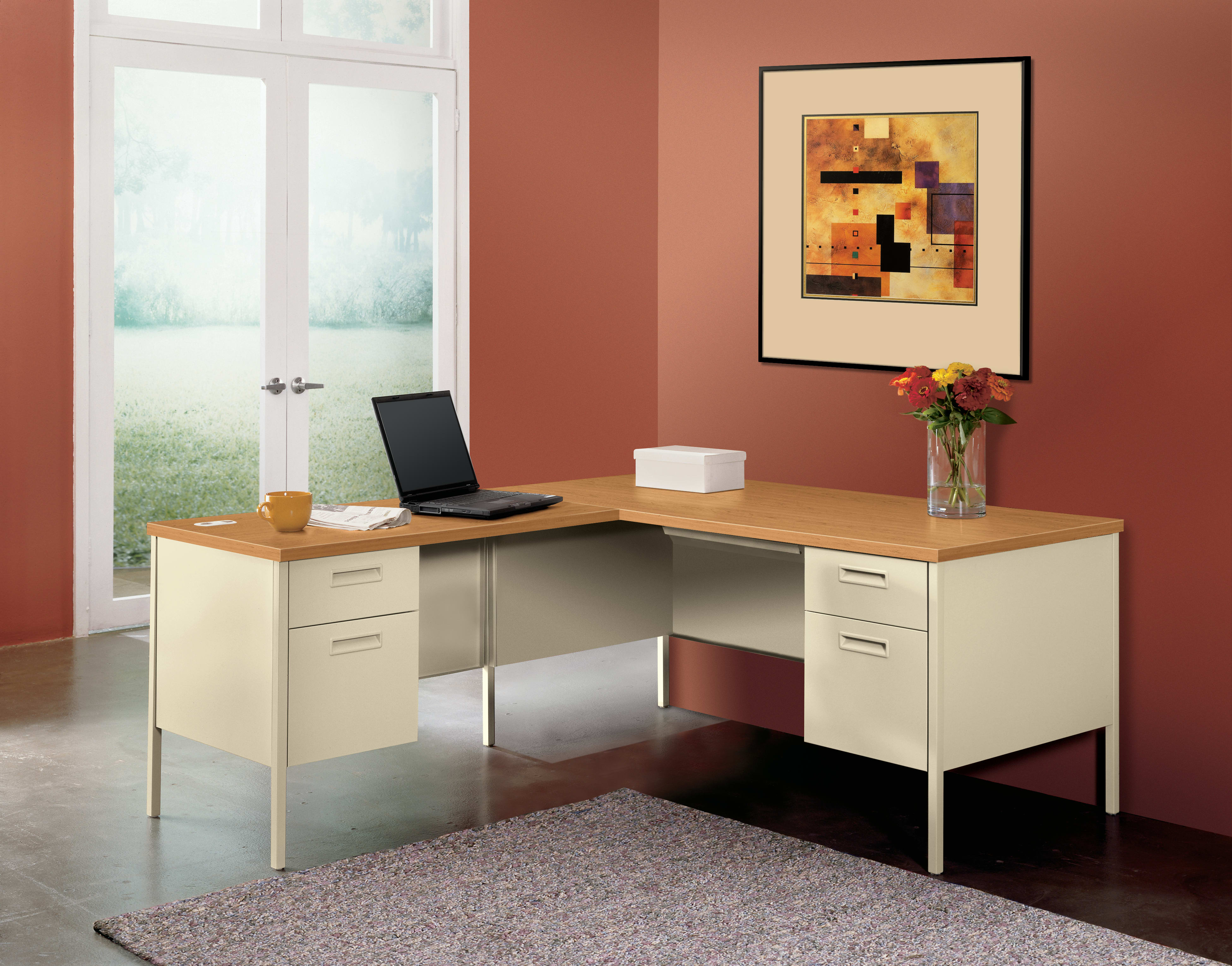 A modern and minimalist home office setup with a wooden desk, a laptop, and a decorative artwork on the wall, set against a warm-toned wall and a view of the outdoors through a window.