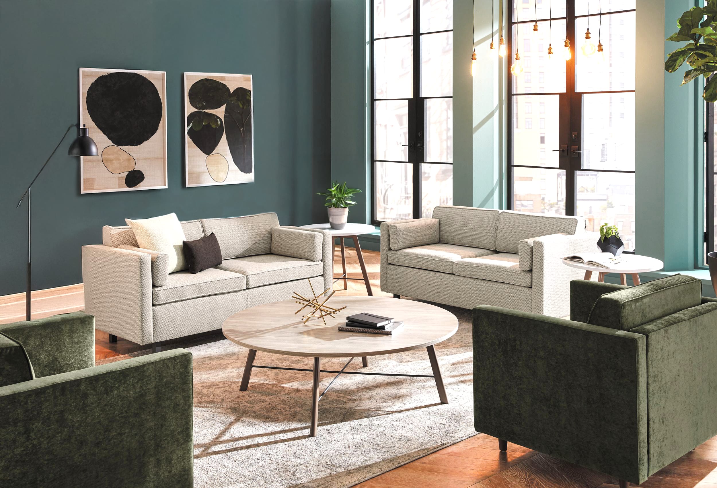 A cozy and stylish living room with neutral-toned sofas, abstract artwork on the walls, and a round wooden coffee table in the foreground, set against a backdrop of large windows and a lush indoor plant.